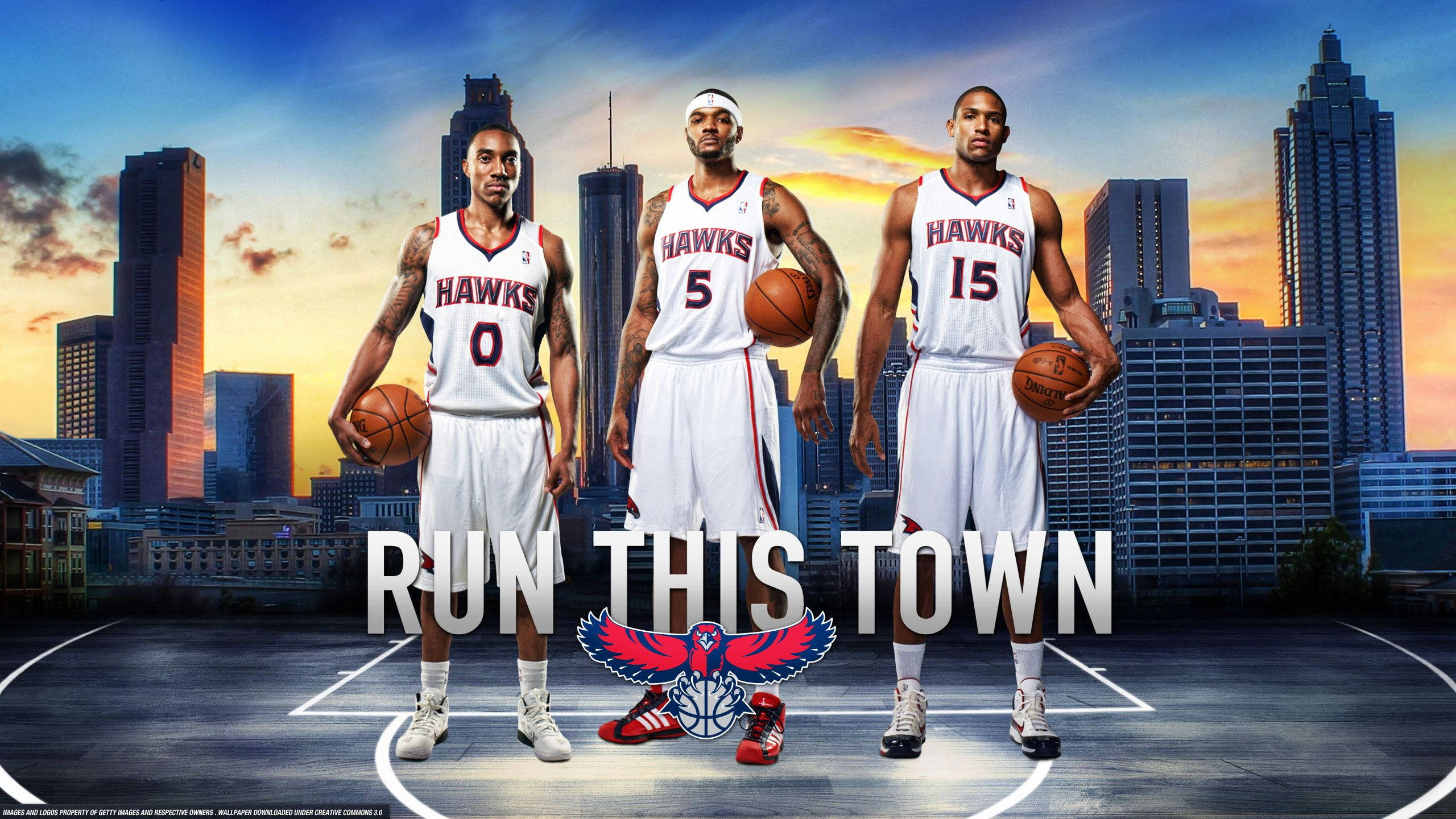 Hawks 桌布 壁紙 — 三名身穿老鷹隊球衣的籃球運動員自信地站在球場上，背後是日落時分的城市天際線。