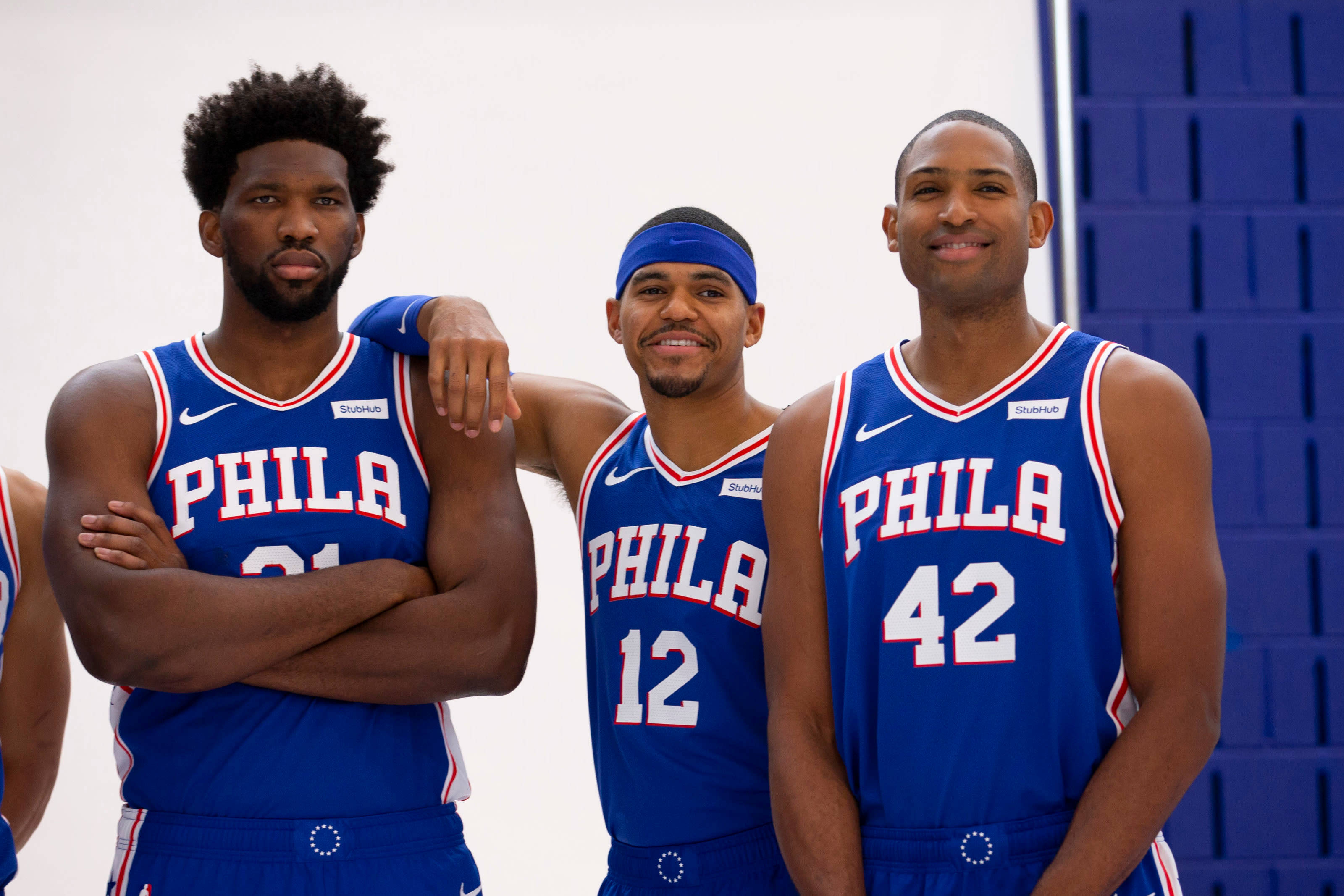 76ers 桌布 壁紙 — 三名身穿藍色球衣的費城76人籃球運動員在純白藍色背景前自信地擺姿勢。