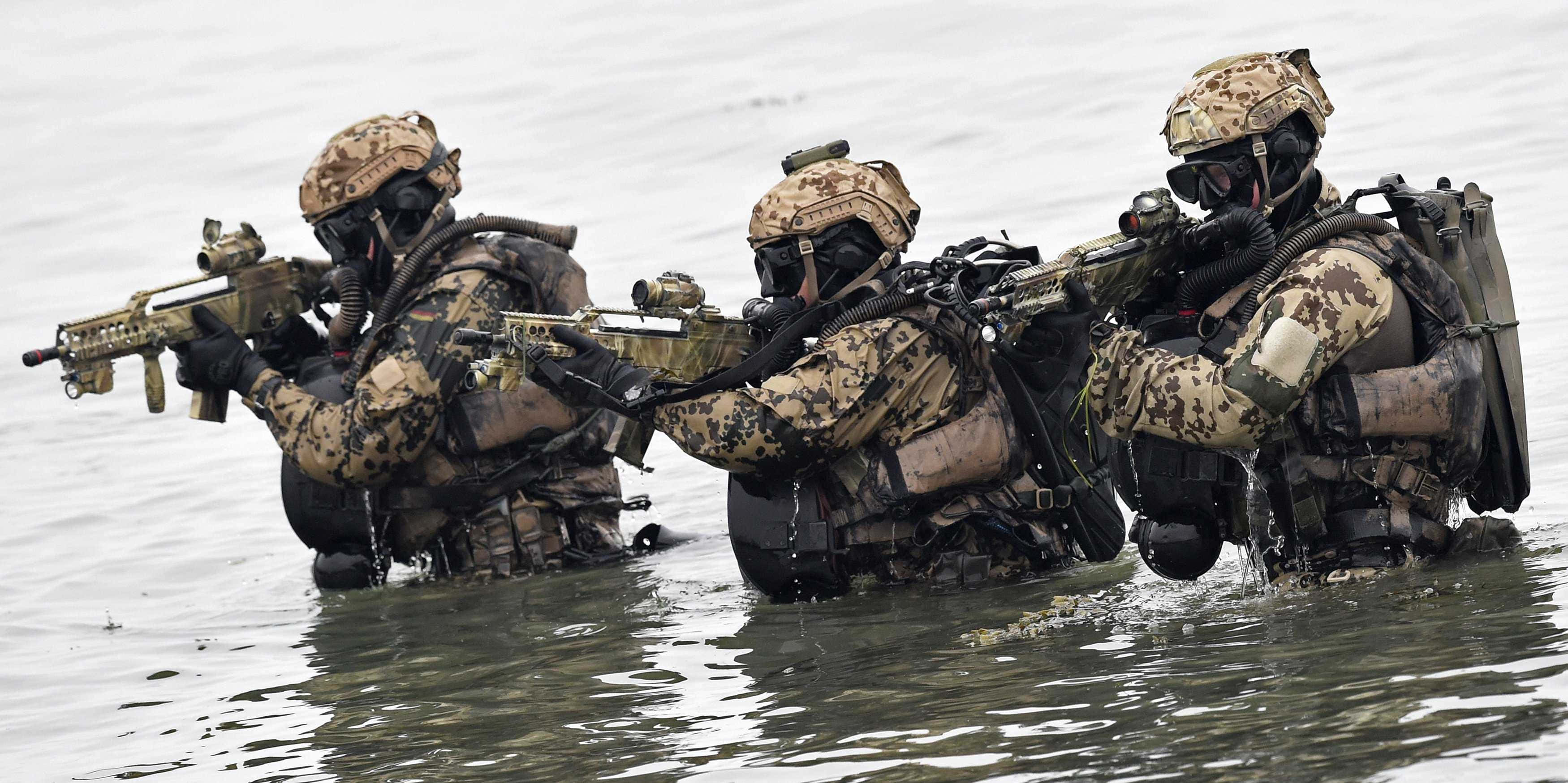 Special Forces 桌布 壁紙 — 三名身穿迷彩裝備的士兵在渾水中以戰術隊形持步槍涉水而行。