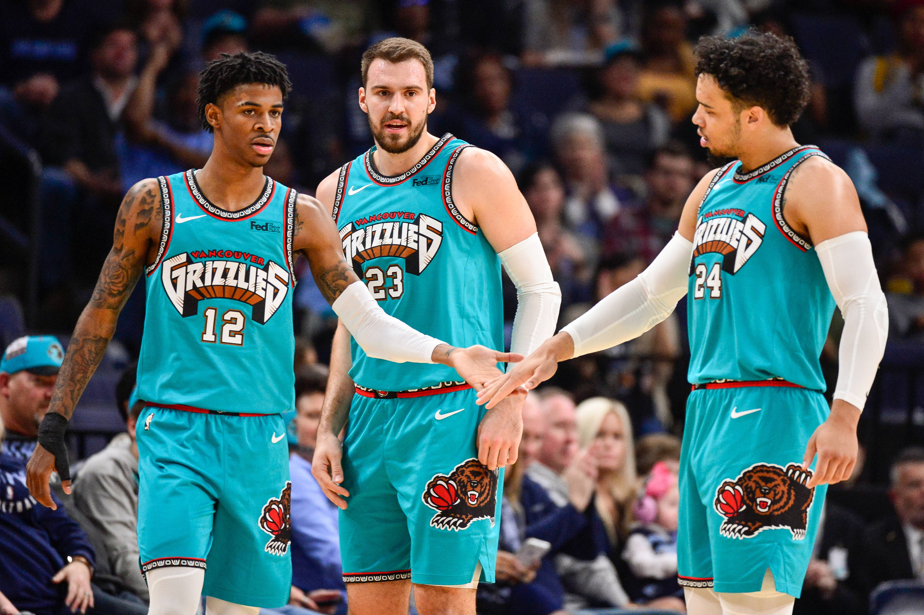 Grizzlies 桌布 壁紙 — 三名身穿青綠色球衣的曼菲斯灰熊籃球運動員在比賽中手牽手，背景有觀眾。