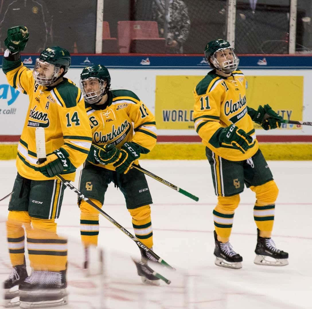 hockey 桌布 壁紙 — 三名身穿黃色和綠色球衣的Clarkson曲棍球運動員在冰上高舉球棍和頭盔慶祝。