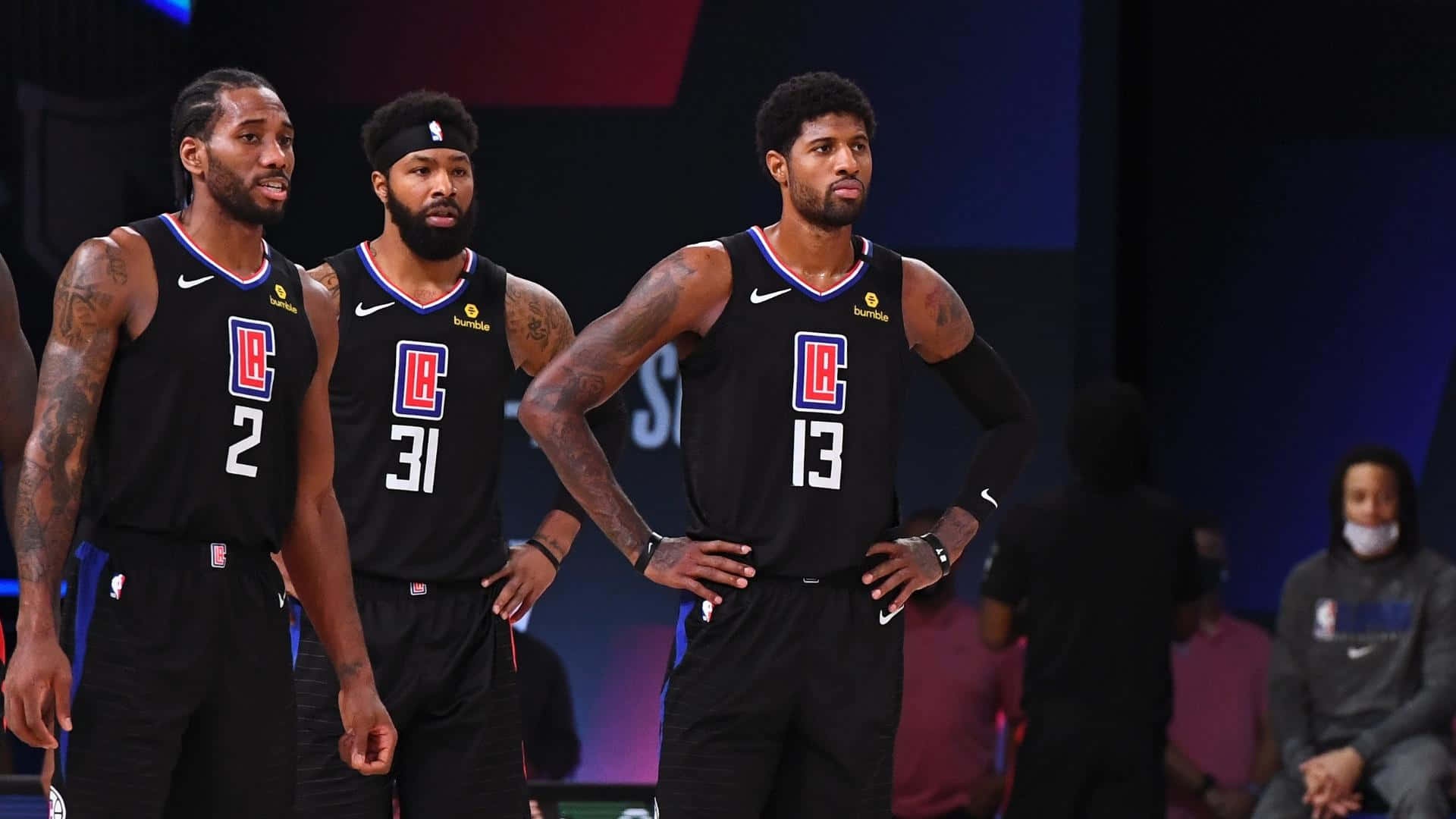 NBA 桌布 壁紙 — 三名身穿黑色球衣的洛杉磯快艇籃球運動員在比賽中專注地站在球場上。
