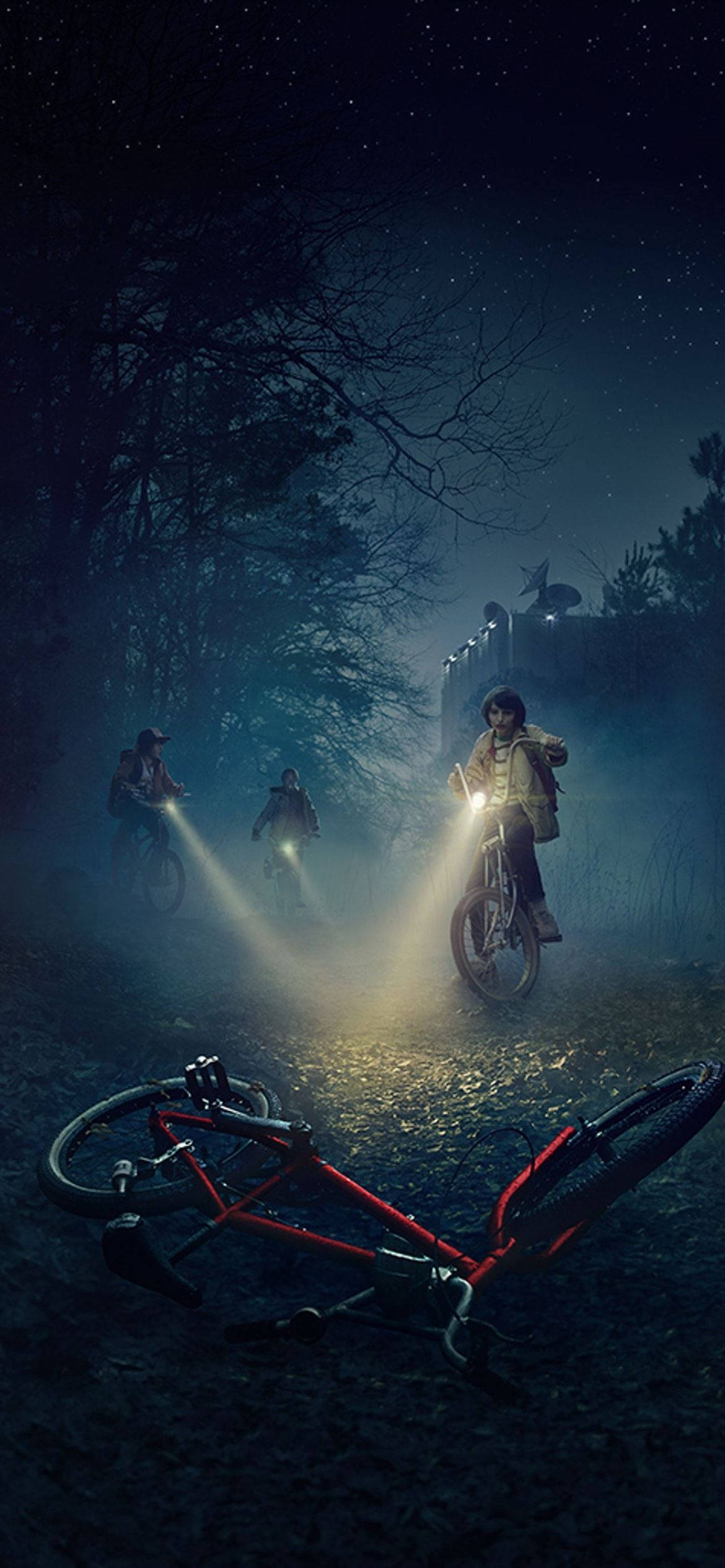Stranger Things Aesthetic 桌布 壁紙 — 三名騎自行車者在夜間穿過霧氣瀰漫的森林，自行車燈光劃破黑暗，前景中有一輛自行車翻倒。