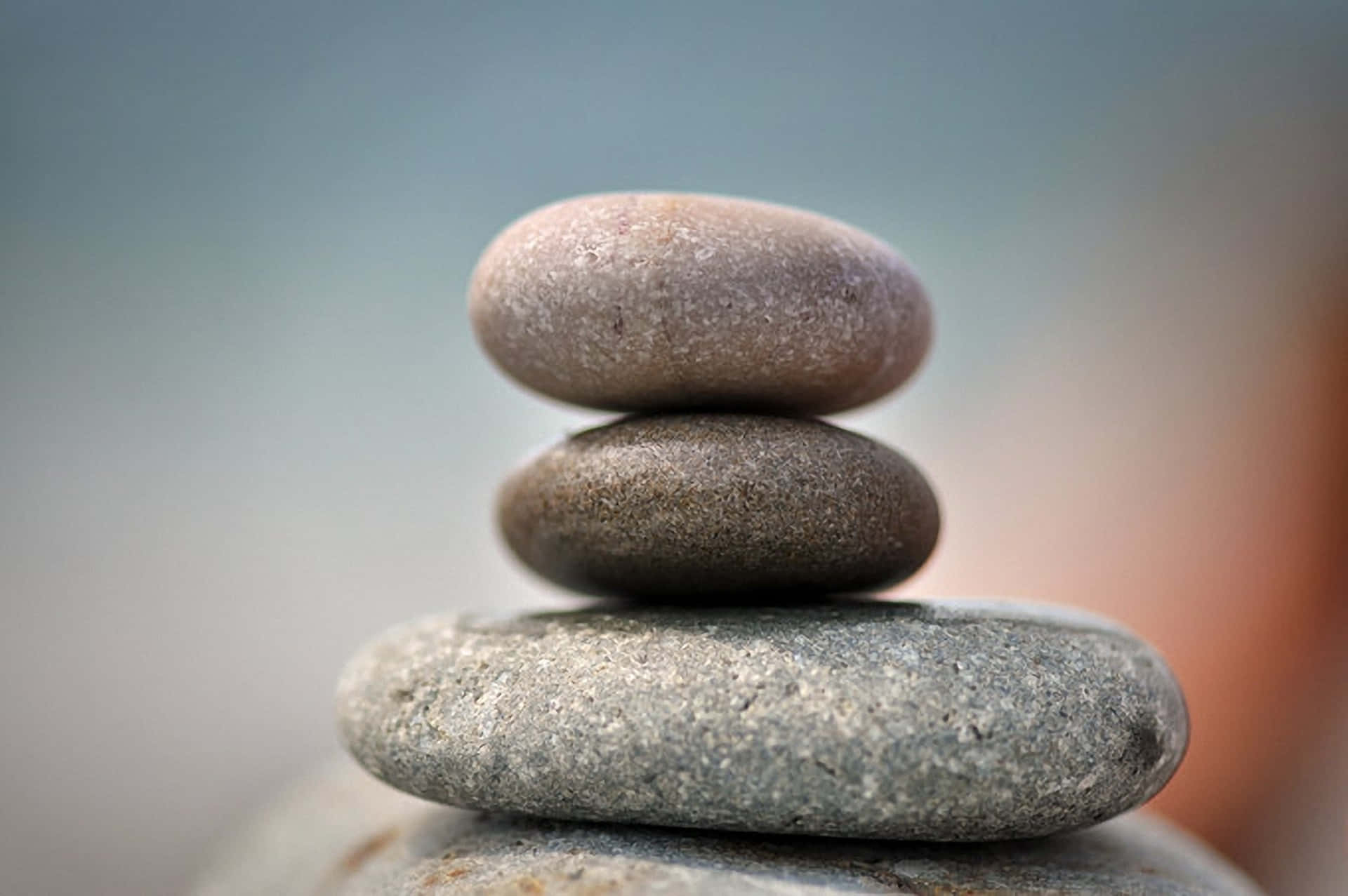 Rocks 桌布 壁紙 — 三塊光滑的河石在柔和模糊的背景前完美和諧地平衡。