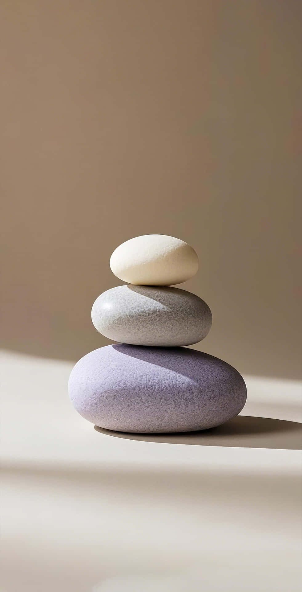 minimalist stacked pebbles on beige calm background 壁紙 — 三塊光滑的石頭，薰衣草灰色和奶油色，在柔和的方向光下完美平衡在一個中性表面上。
