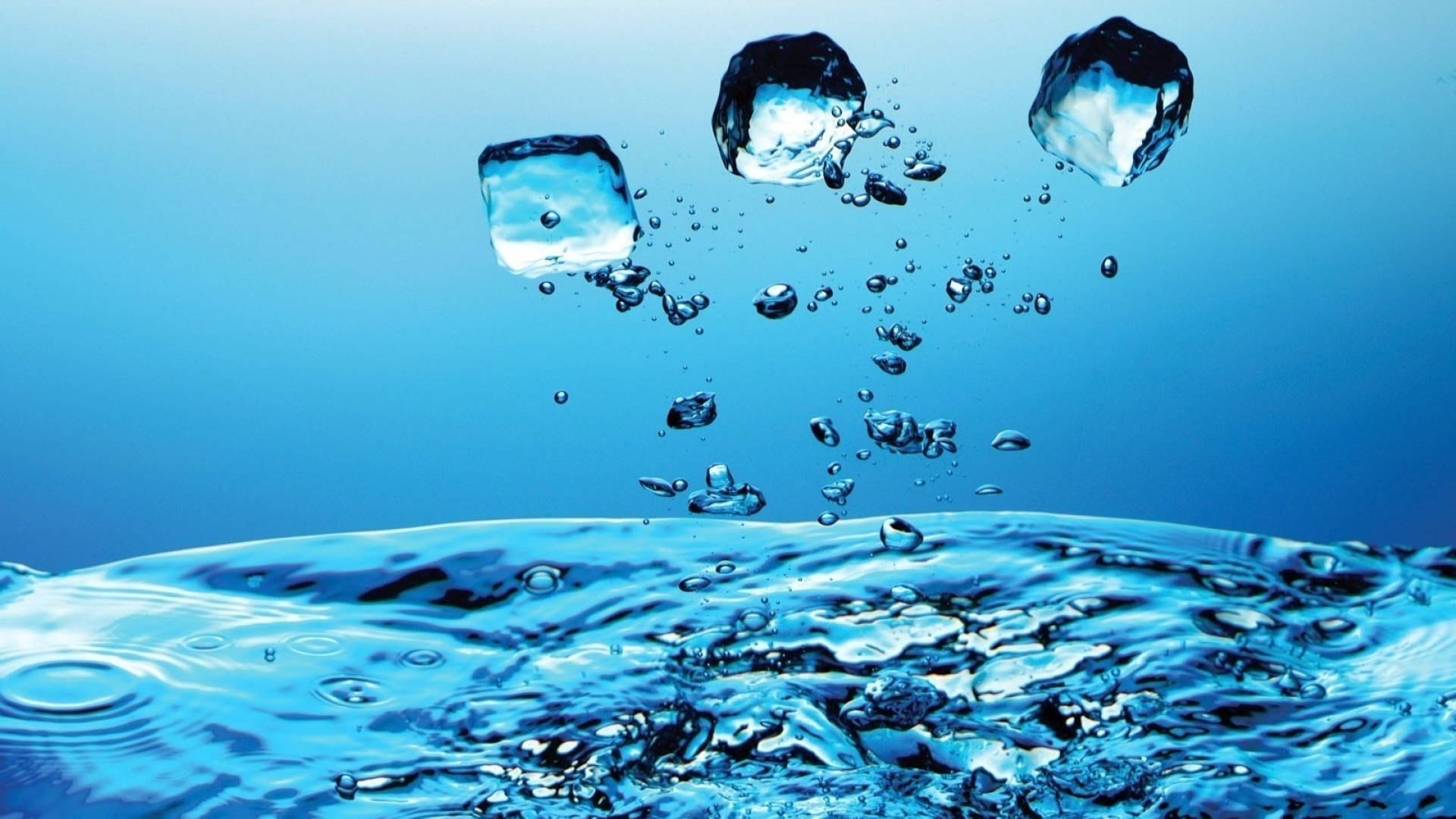 Water Splash 桌布 壁紙 — 三塊冰塊懸浮在漣漪藍色水面上方，帶有閃爍水滴和氣泡。