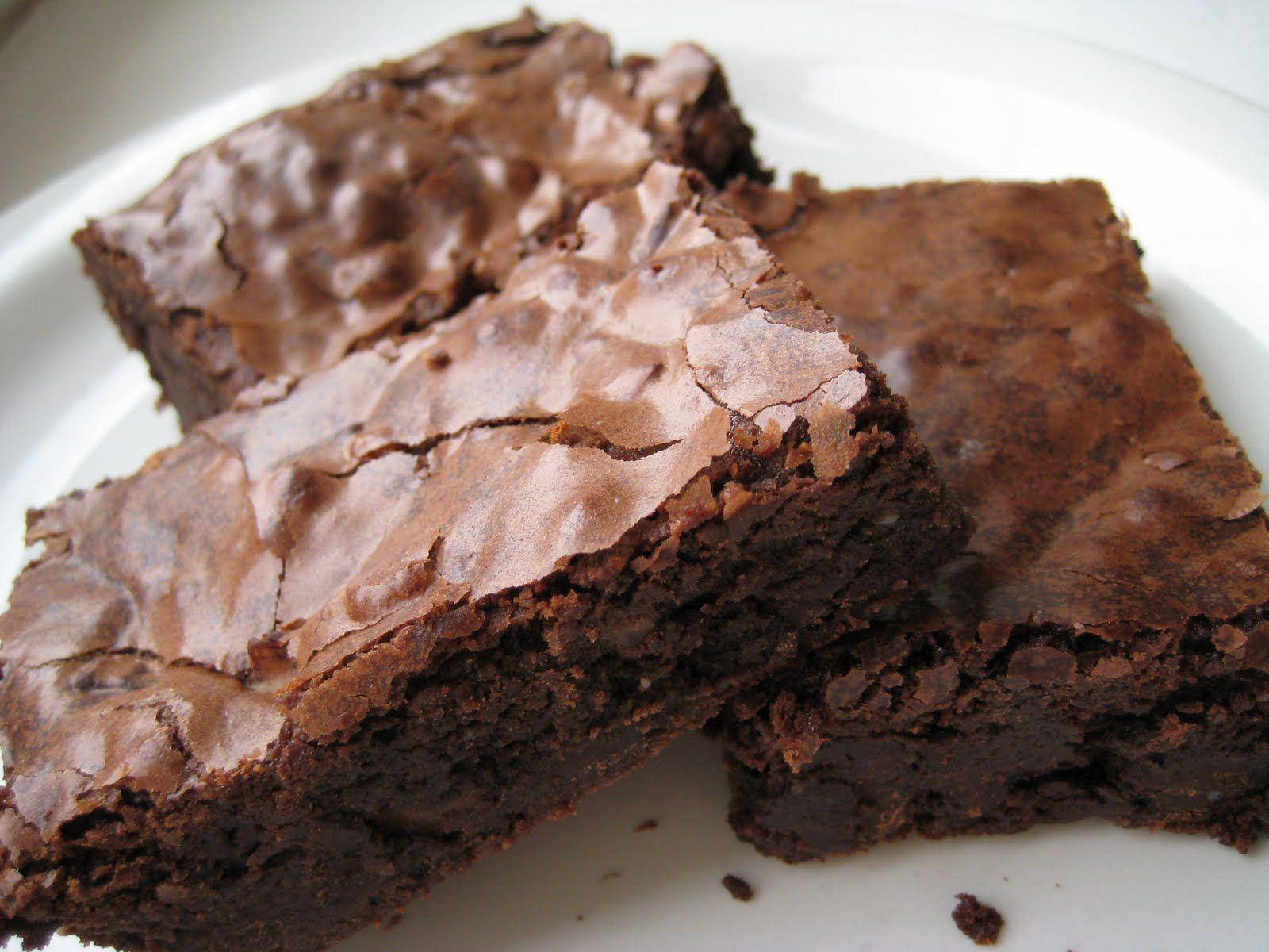 Brownies 桌布 壁紙 — 三塊濃郁軟心的巧克力布朗尼，頂部有裂紋，放在白色盤子上。