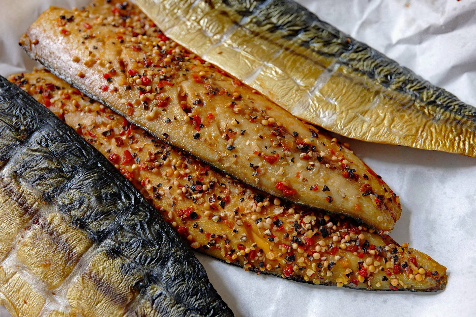 魚 桌布 壁紙 — 三塊烤鯖魚柳，上面撒上紅辣椒片和芝麻，放在皺巴巴的烘焙紙上。