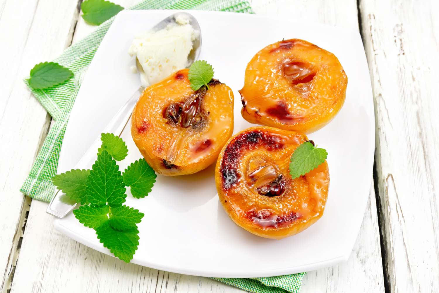 Quince 桌布 壁紙 — 三塊焦糖化的杏子半邊在白色盤子上閃閃發光，搭配新鮮薄荷和一球香草冰淇淋。