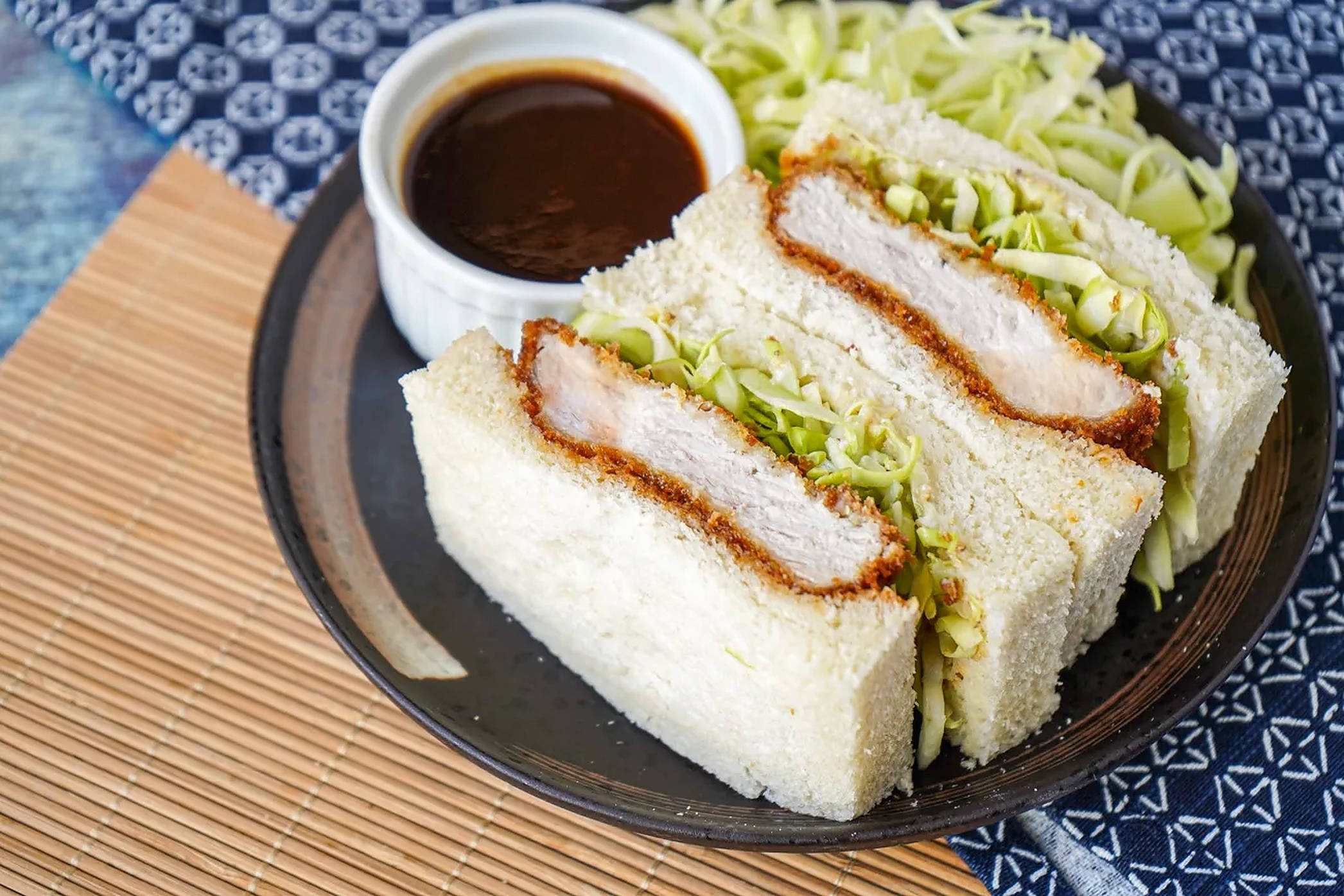 三明治 桌布 壁紙 — 三塊脆皮炸雞三明治，搭配高麗菜絲和沾醬，放在深色盤子上。