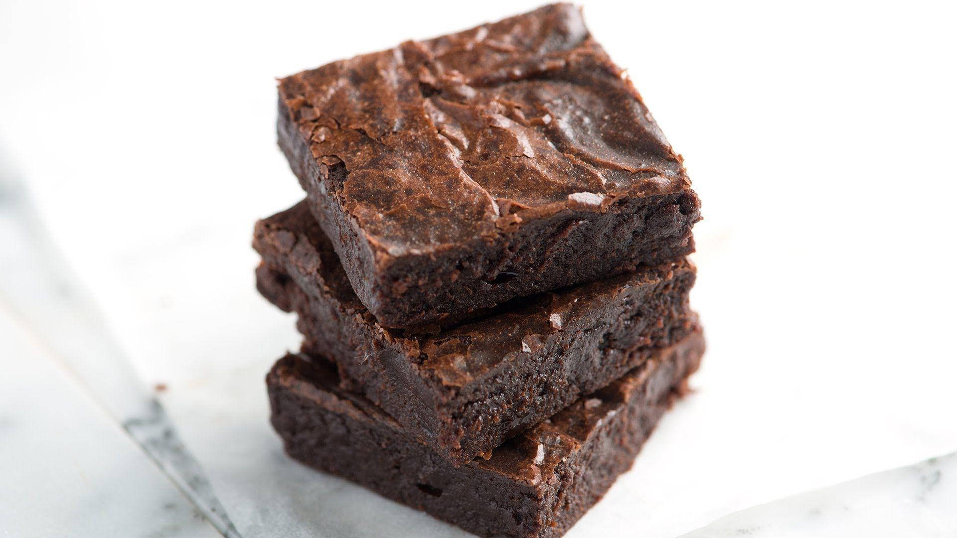 Brownies 桌布 壁紙 — 三塊軟心巧克力布朗尼堆疊在白色大理石表面上，背景柔和模糊。