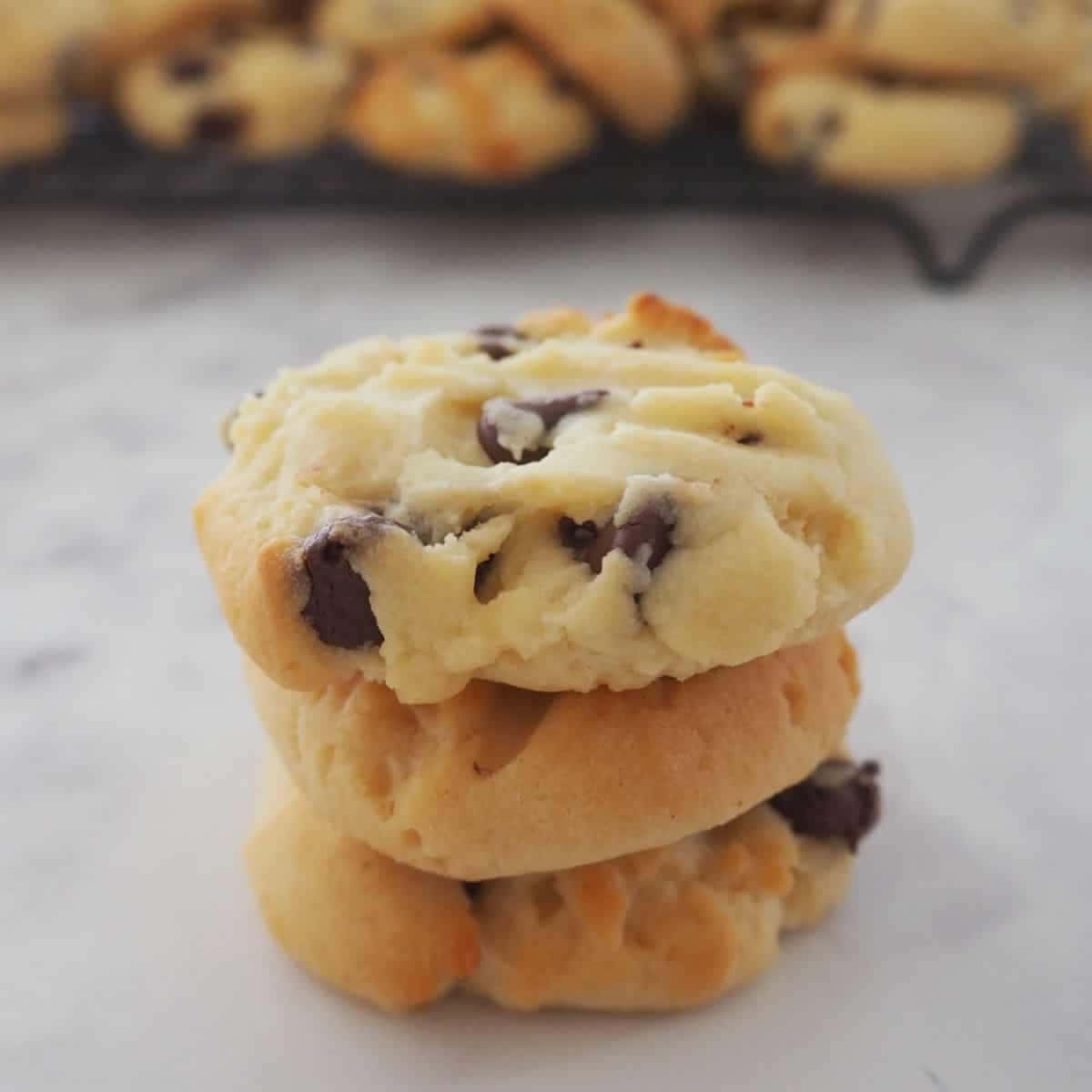 Biscuit 桌布 壁紙 — 三塊金黃色的巧克力曲奇堆疊在大理石表面上，背景中還有更多曲奇模糊可見。