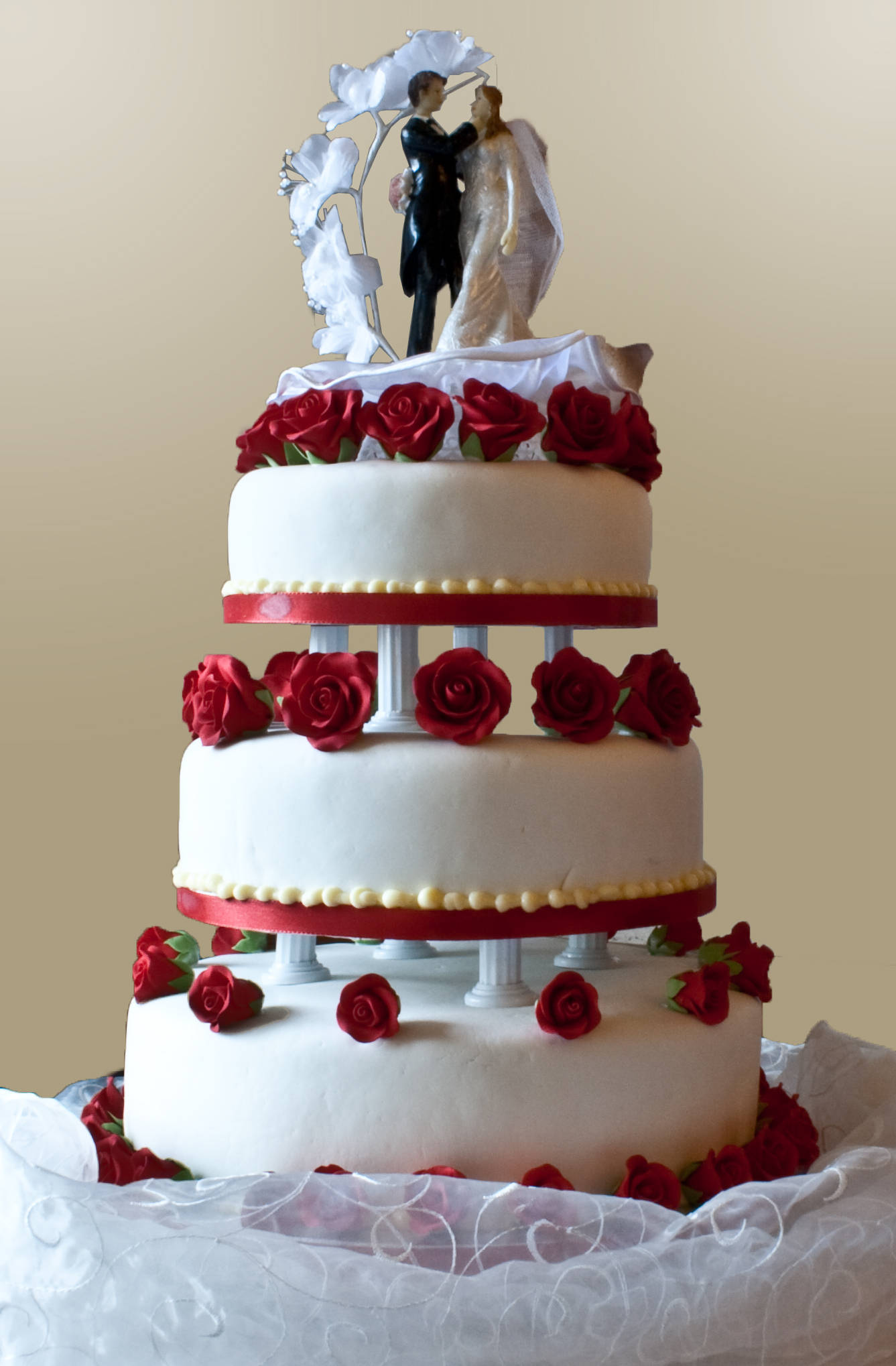 Wedding 桌布 壁紙 — 三層白色結婚蛋糕，裝飾紅玫瑰，頂部有花拱下的新郎新娘公仔。