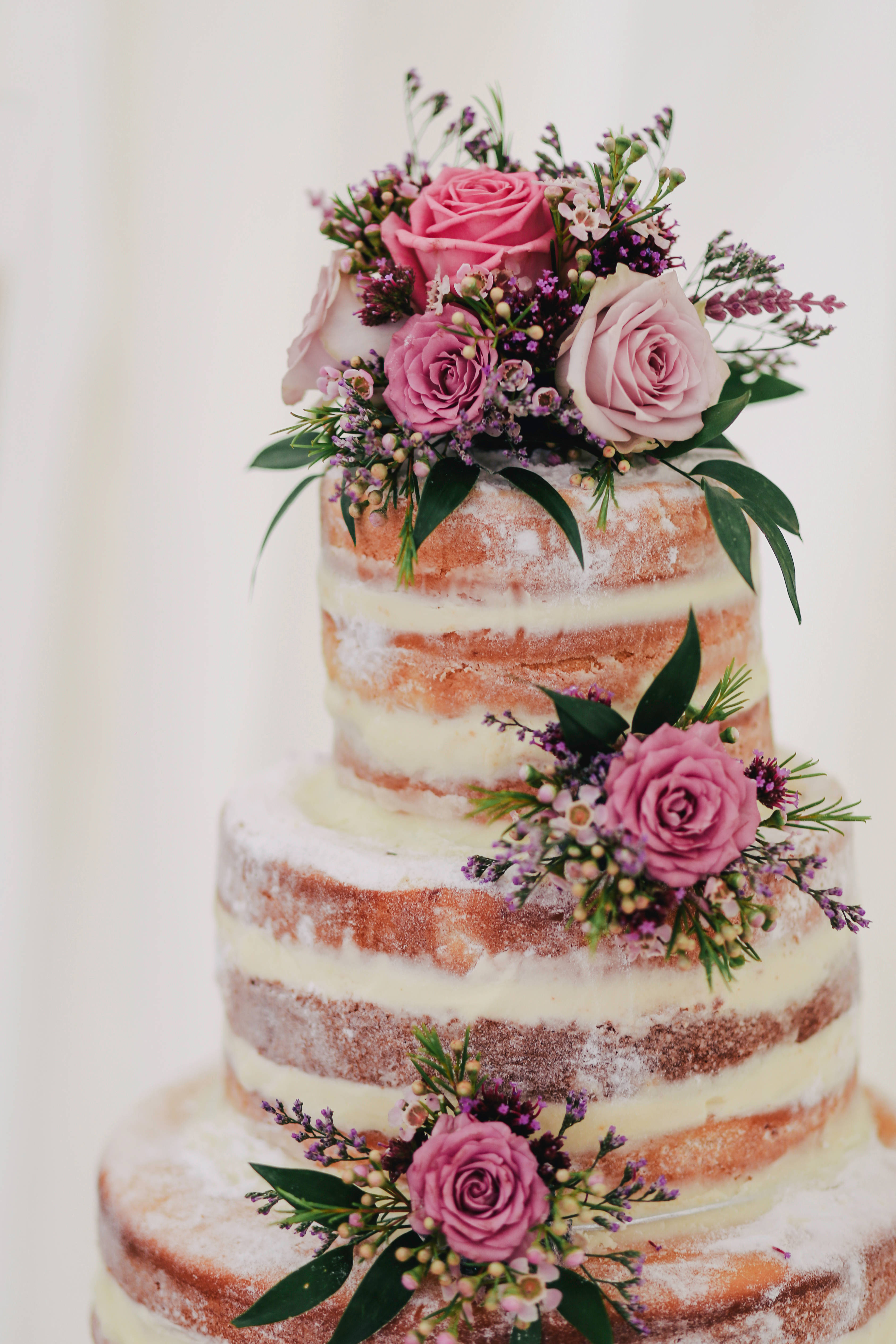 Wedding 桌布 壁紙 — 三層裸體婚禮蛋糕，飾有粉紅玫瑰和紫色薰衣草花朵，背景為柔和的白色。