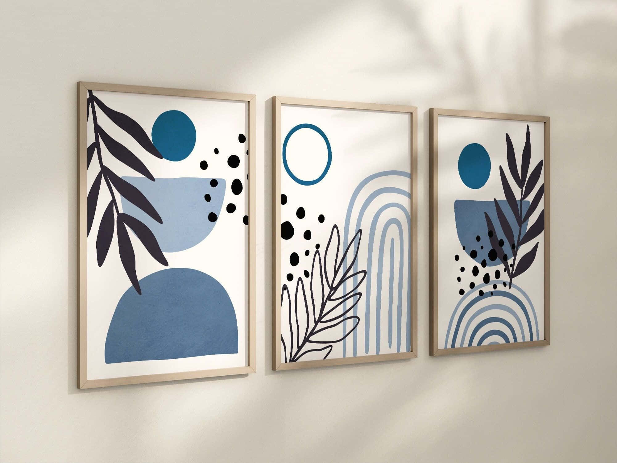 Minimalist Painting 桌布 壁紙 — 三幅帶有藍色形狀、黑色葉子和點點的裱框抽象藝術品掛在米色牆上，投下柔和陰影。