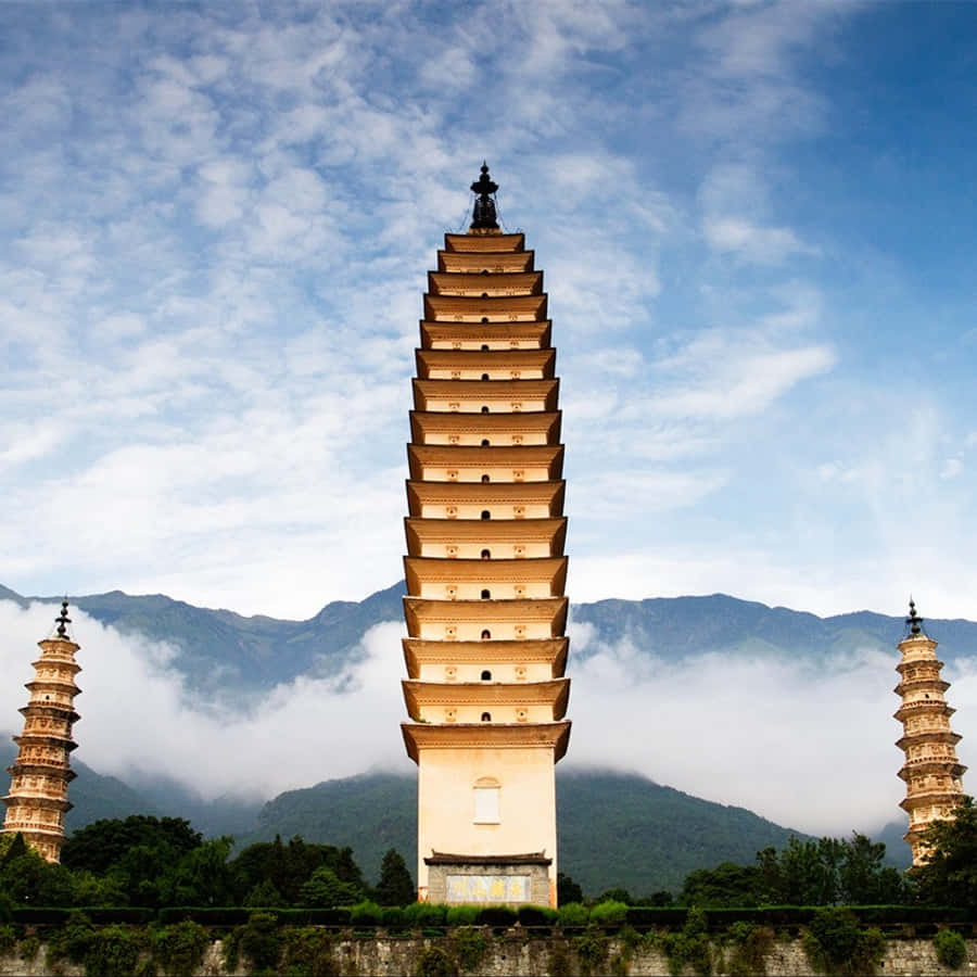 建築 桌布 壁紙 — 三座古塔在藍天白雲和霧氣繚繞的山巒背景下巍峨聳立。