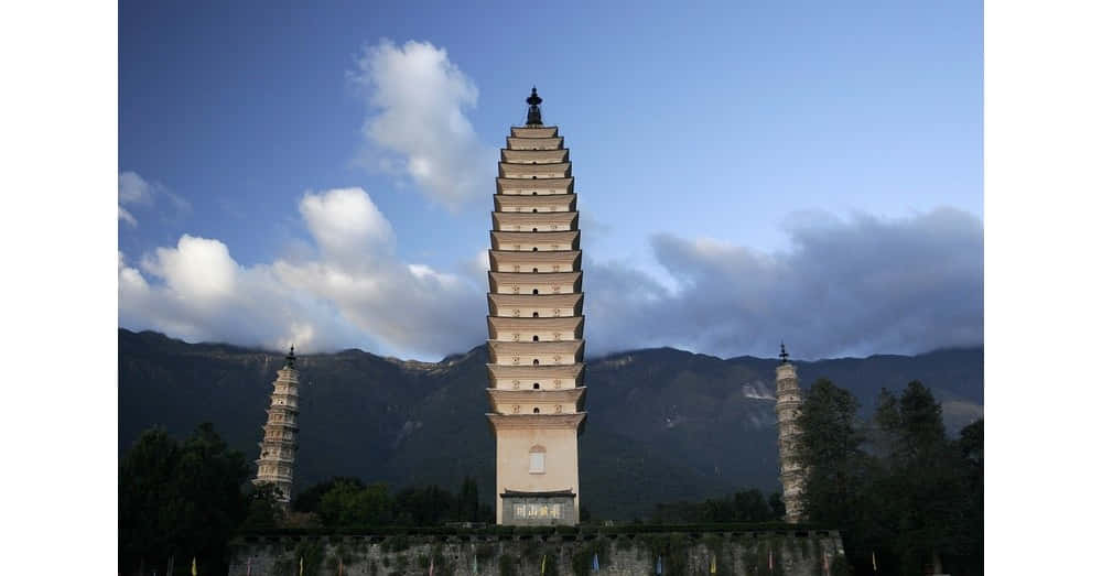 廟宇 桌布 壁紙 — 三座古老的石塔在部分多雲的藍天下，以戲劇性的山脈為背景聳立。