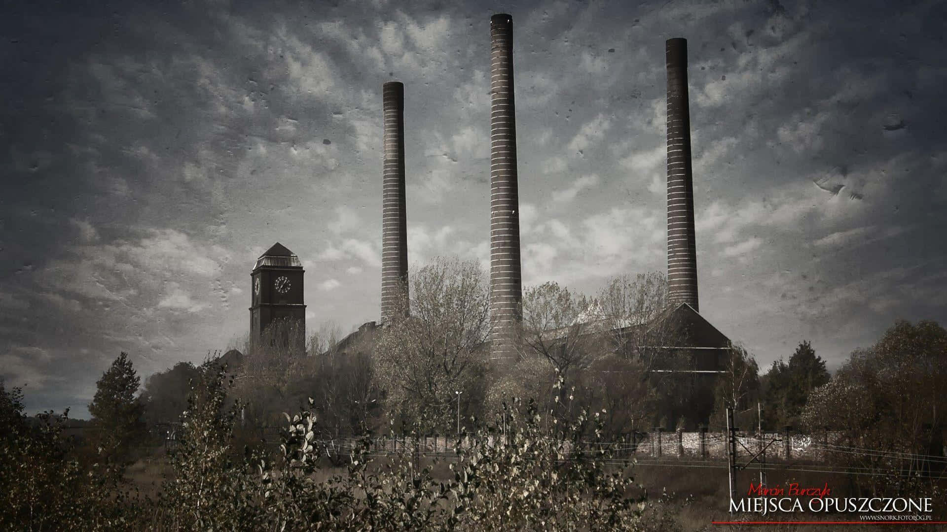 Industrious 桌布 壁紙 — 三座高聳的煙囪和一座鐘樓從廢棄的工業綜合體中升起，在暴風雨般的灰色天空下。