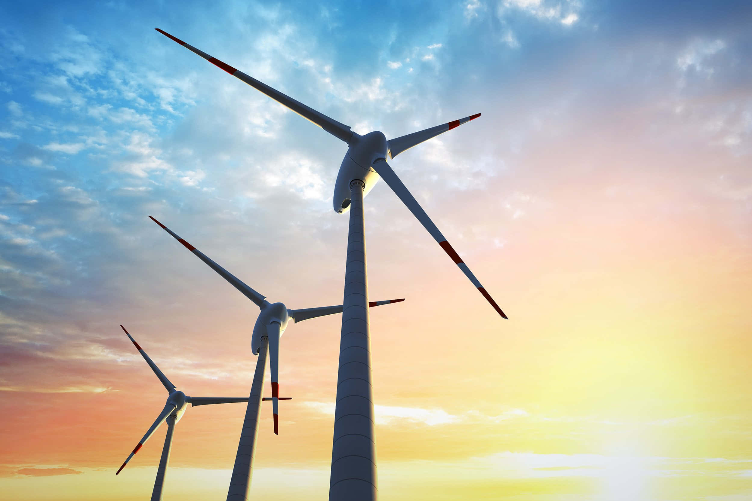 Energy 桌布 壁紙 — 三座高聳的風力發電機矗立在充滿活力的日落天空下，天空中有橙色、粉紅色和藍色的雲彩條紋。