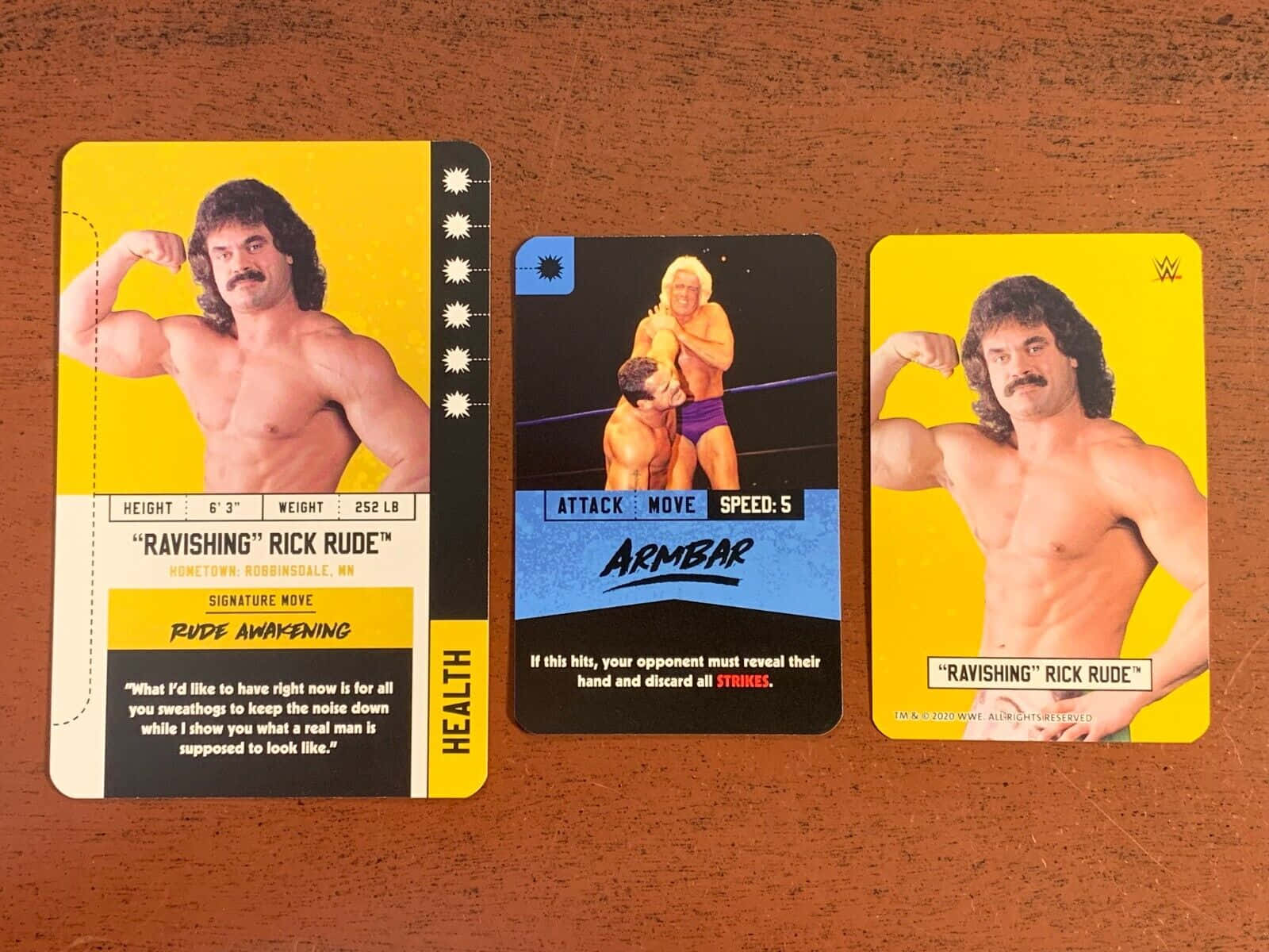 摔角 桌布 壁紙 — 三張 Rick Rude 的復古 WWE 收藏卡展示在木質表面上，展示了他的招牌動作和統計數據。