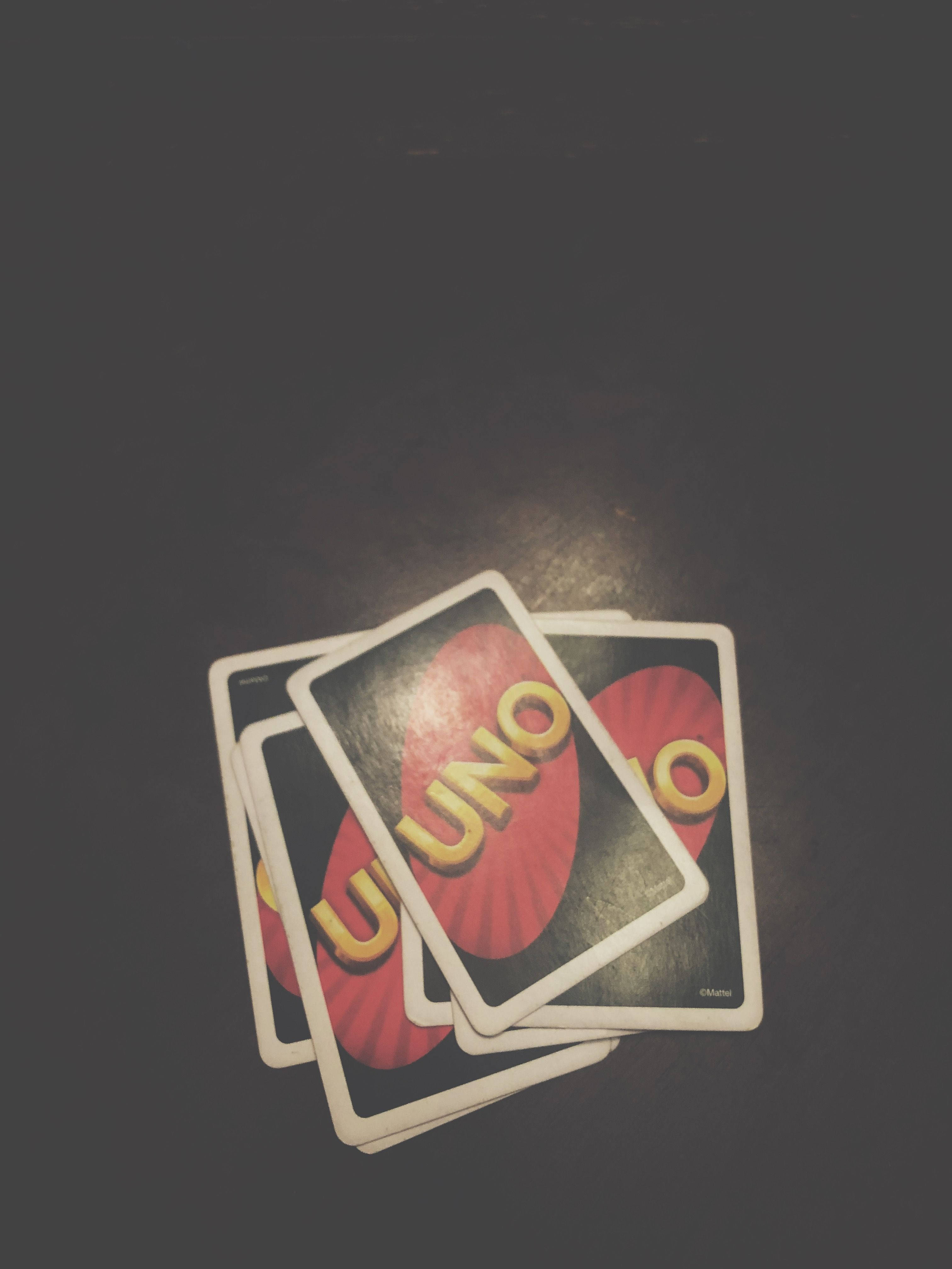 Uno 桌布 壁紙 — 三張Uno卡在黑暗表面上展開，在聚焦的聚光燈下形成戲劇性的陰影。
