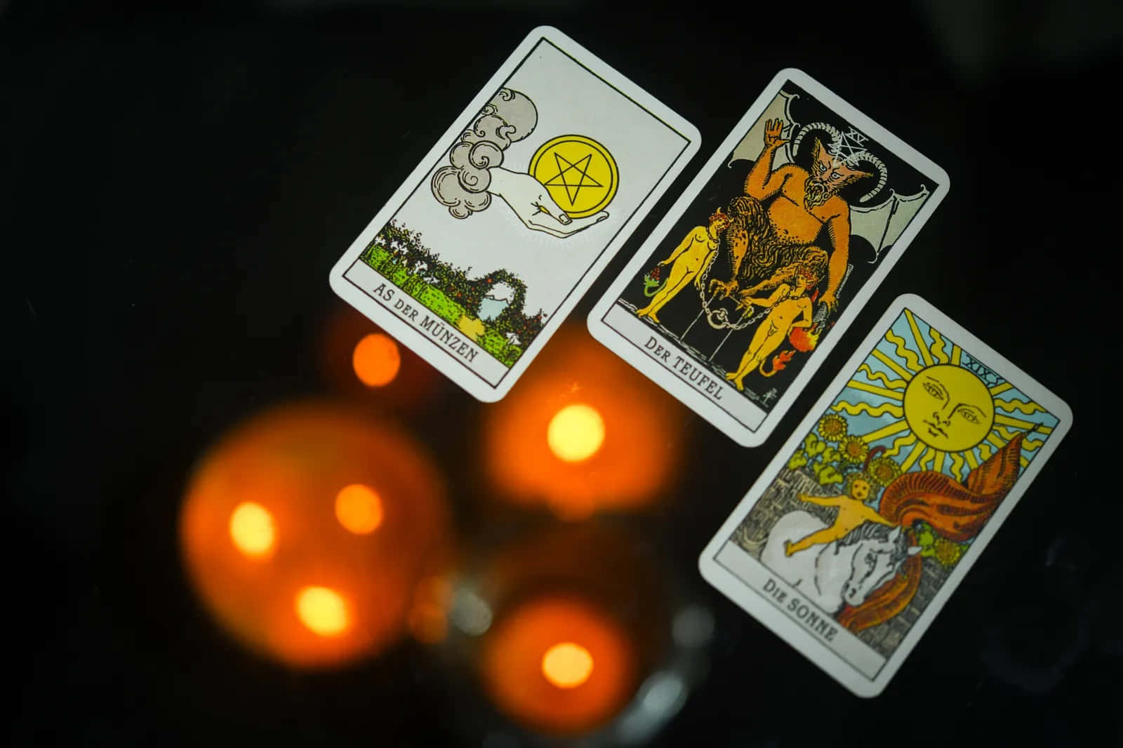 Tarot Card 桌布 壁紙 — 三張塔羅牌「愚者」、「惡魔」和「太陽」在溫暖的燭光下，於黑暗背景中閃耀。