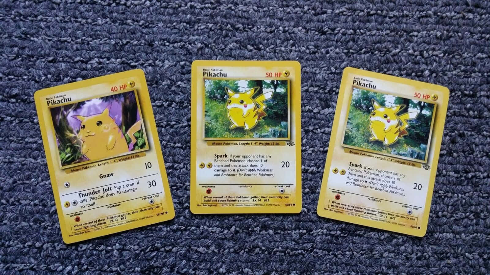 Pokemon Card 桌布 壁紙 — 三張復古皮卡丘寶可夢卡牌放在有紋理的藍色地毯上，展示不同的藝術作品和HP值。