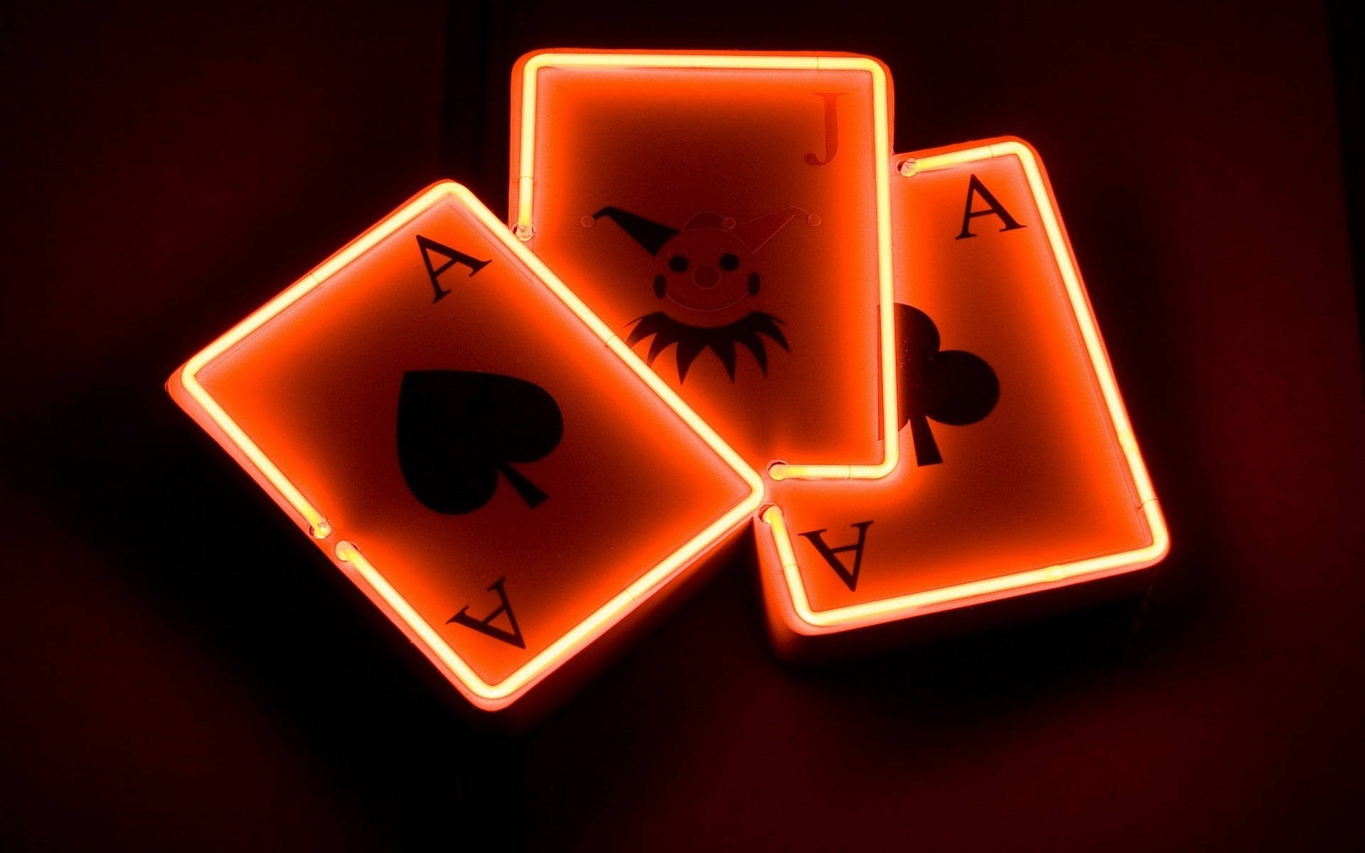 Playing Cards 桌布 壁紙 — 三張發光的霓虹撲克牌：黑桃A、梅花J和梅花A，在黑暗背景中閃耀。