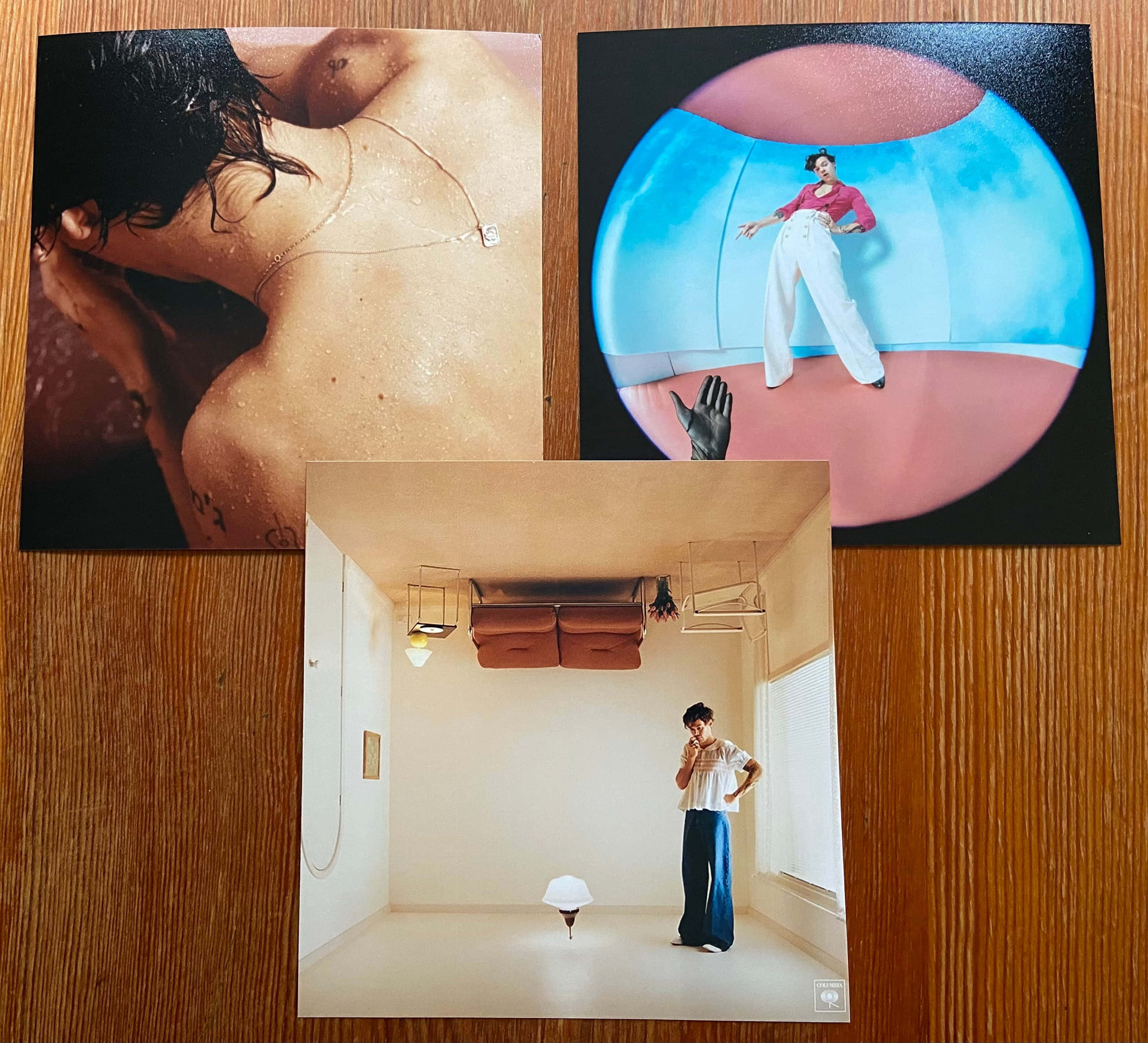 Album Cover 桌布 壁紙 — 三張超現實攝影印刷品展示了一個濕背、一個在泡泡中的女人和一個在倒置房間中的男人，全部放在木質表面上。