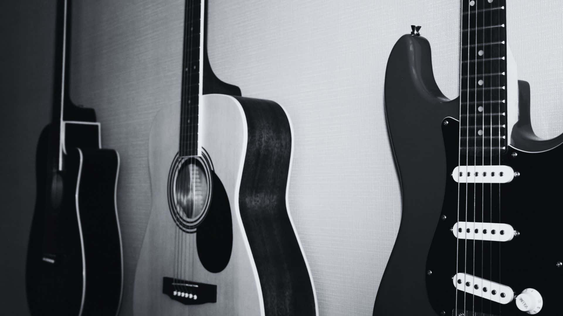 Black And White Guitar 桌布 壁紙 — 三把吉他，包括木吉他和電吉他，以單色調靠在一面有紋理的牆上。