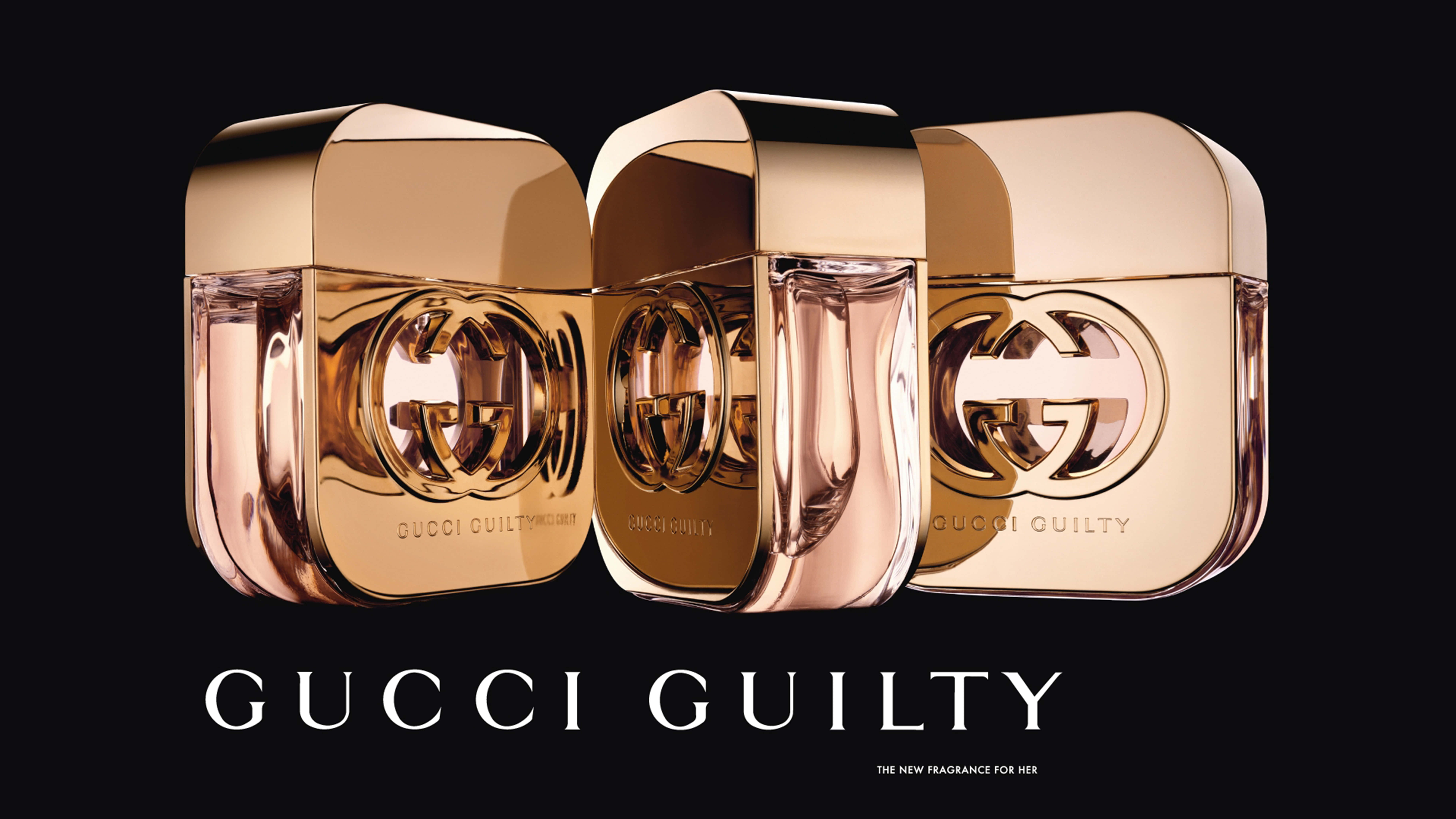 高清 桌布 壁紙 — 三支玫瑰金色Gucci Guilty香水瓶在黑色背景上閃耀，帶有醒目的白色品牌標識。