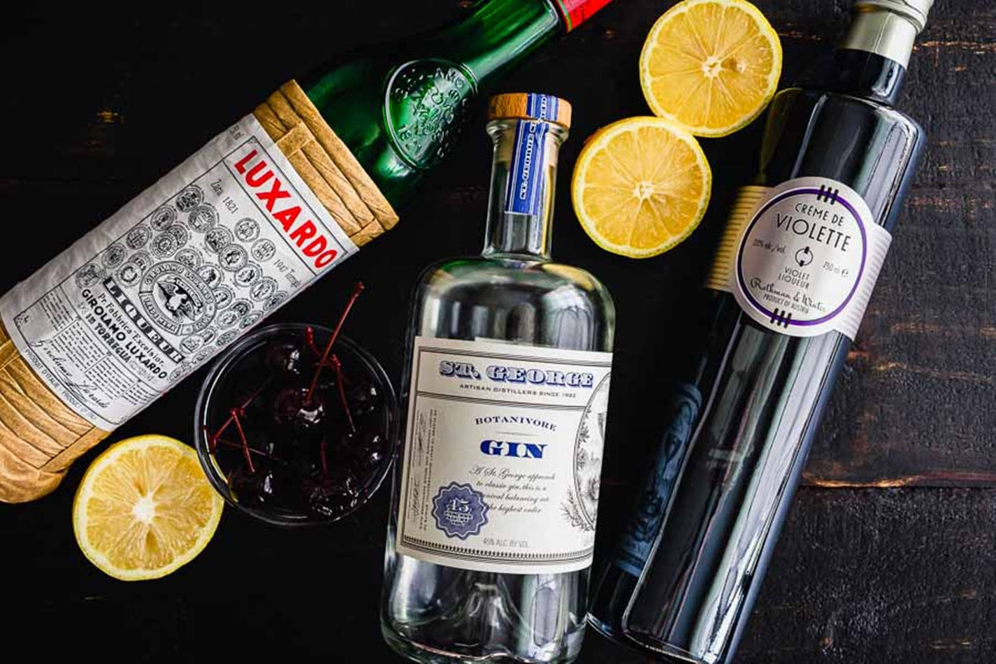 Drink 桌布 壁紙 — 三支高級烈酒瓶和檸檬片排列在深色木質表面上，配有一個雞尾酒杯。