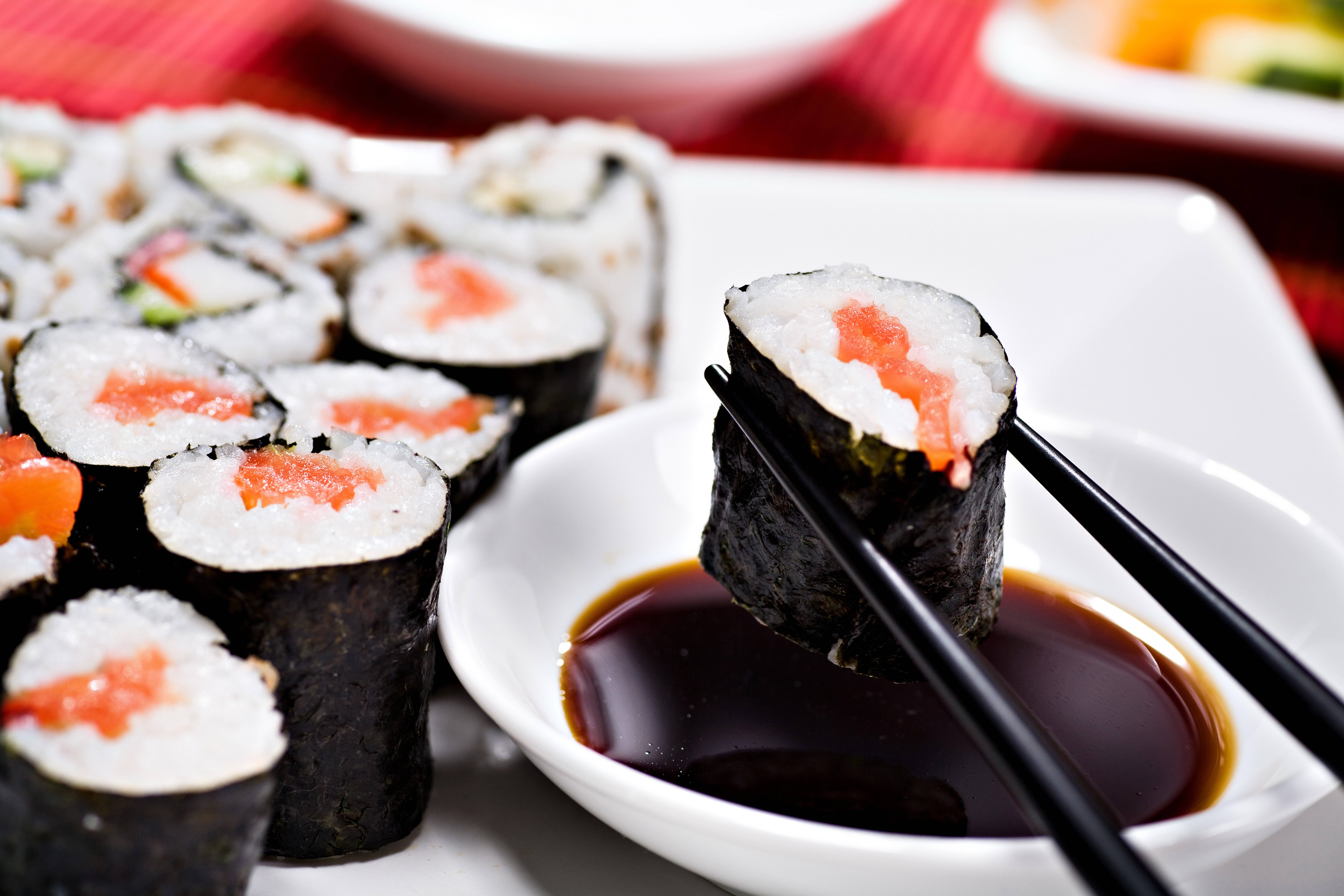 Sushi 桌布 壁紙 — 三文魚壽司卷用黑色筷子蘸醬油的特寫。