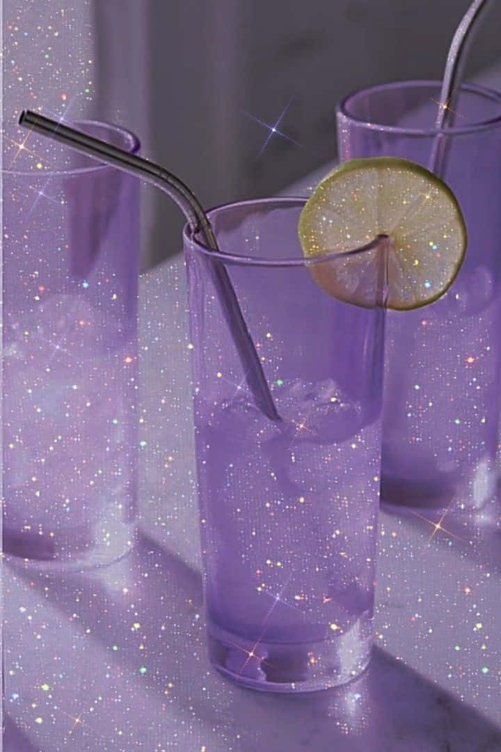 Violet Aesthetic 桌布 壁紙 — 三杯紫色閃粉飲品，配上萊姆片和金屬吸管，在大理石表面上閃閃發光。