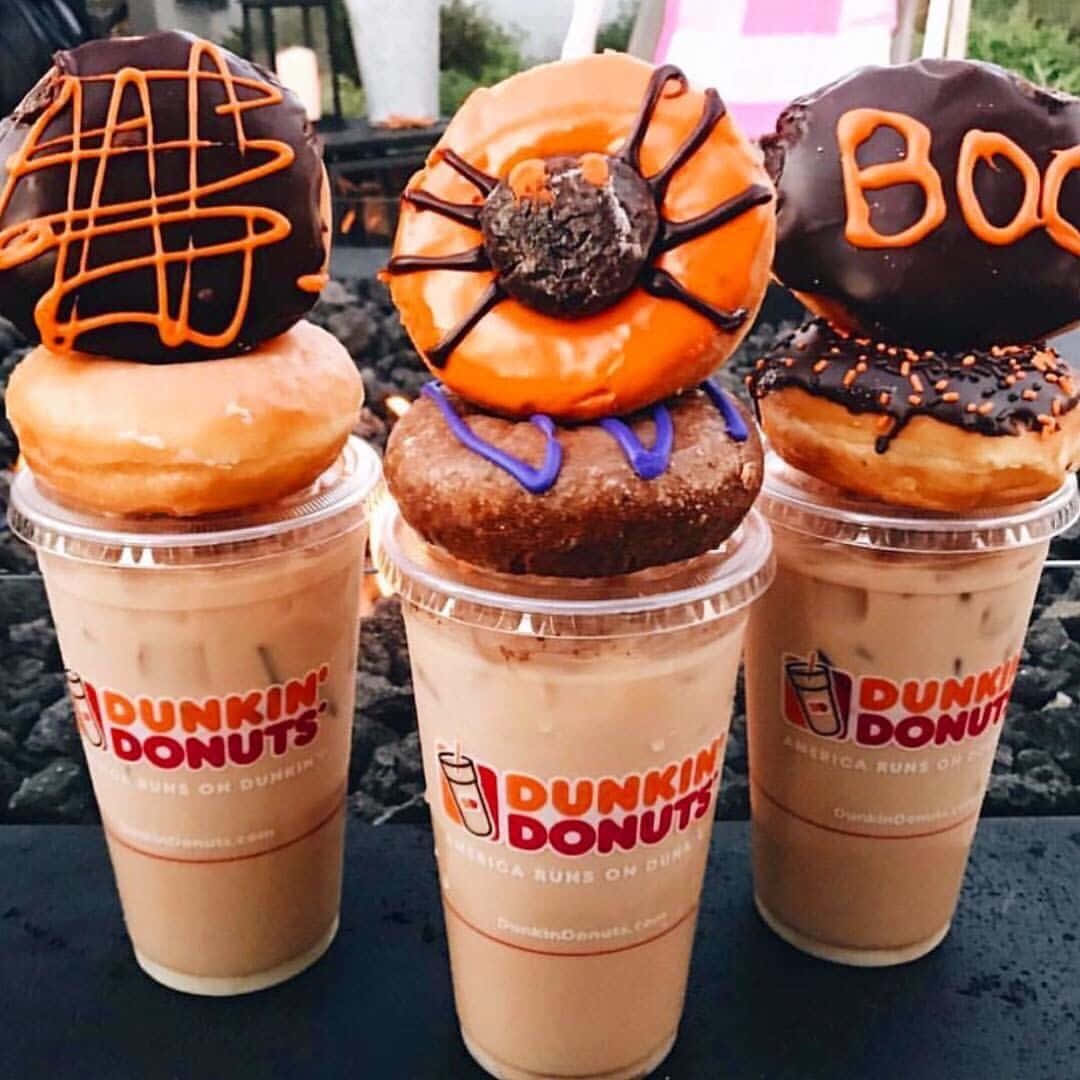 Dunkin Donuts 桌布 壁紙 — 三杯萬聖節主題的Dunkin' Donuts冰咖啡，上面放著帶有蜘蛛網、Boo字母和橙色淋醬的恐怖甜甜圈。