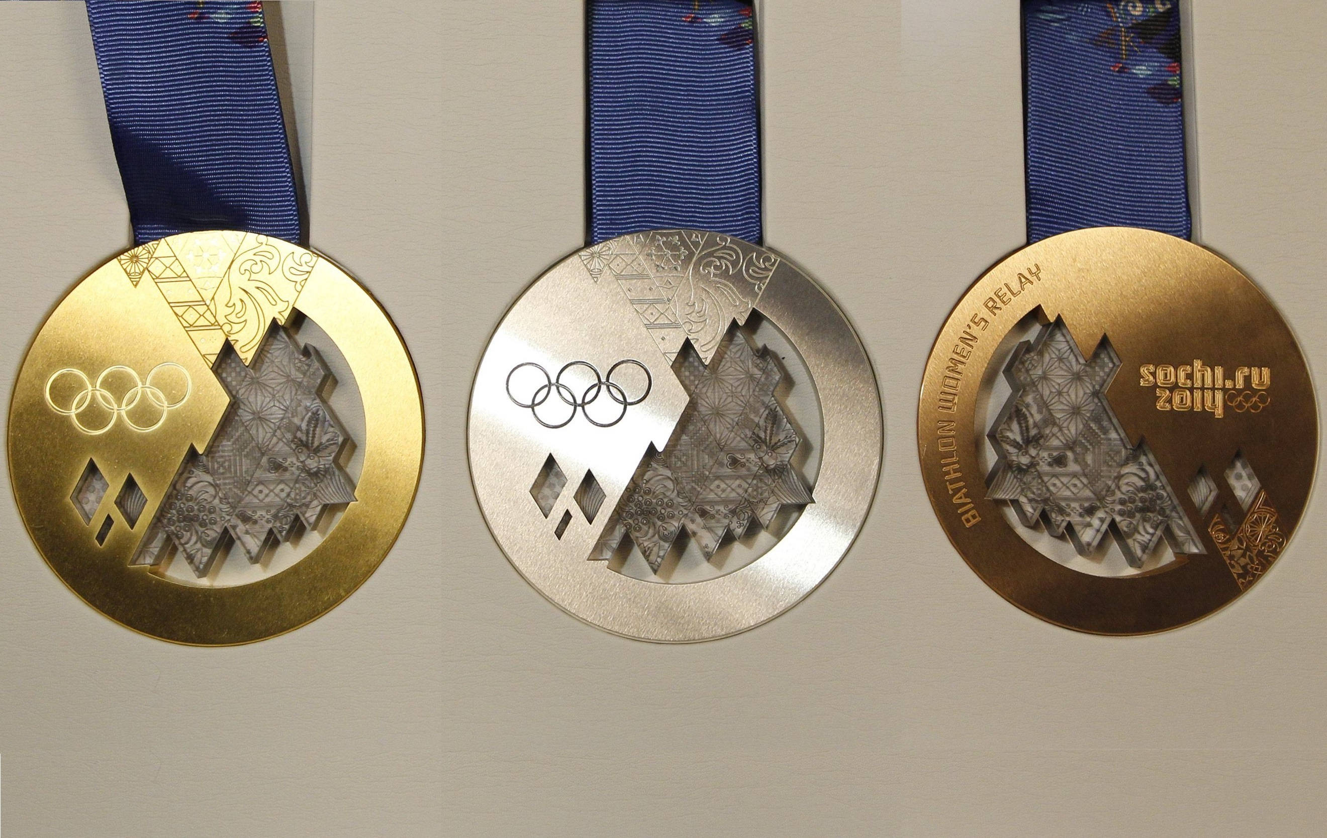 Olympics 桌布 壁紙 — 三枚奧運獎牌金銀銅，搭配藍色絲帶，展示在純色牆上。