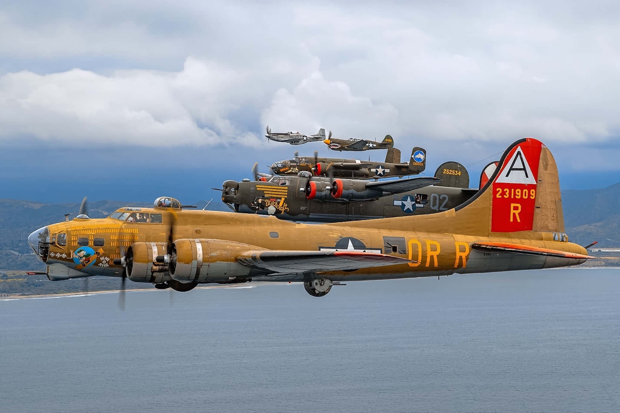 World War 2 桌布 壁紙 — 三架復古軍用轟炸機在陰天下的平靜海洋上空編隊飛行。