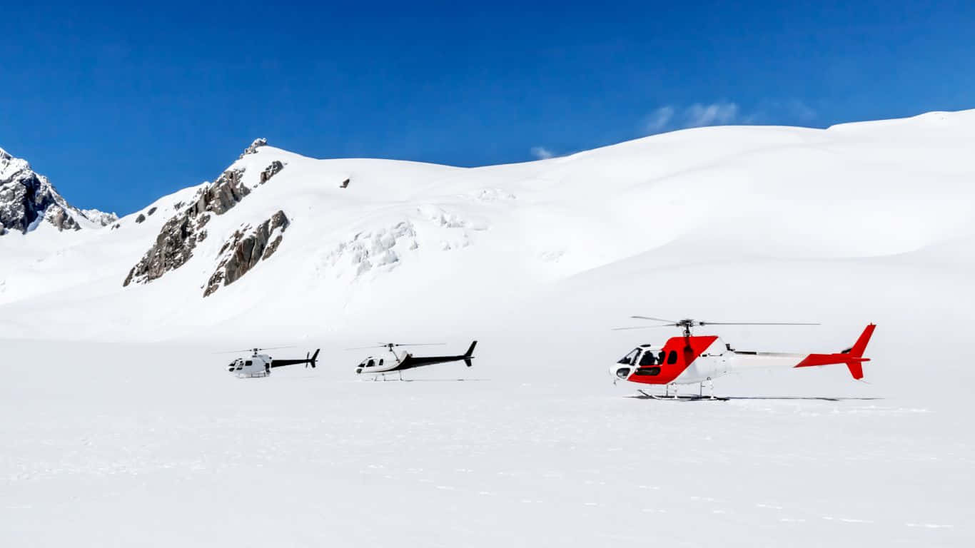 1366x768 Helicopters 桌布 壁紙 — 三架直升機在廣闊的雪山平原上休息，天空清澈湛藍，遠處有岩石山峰。