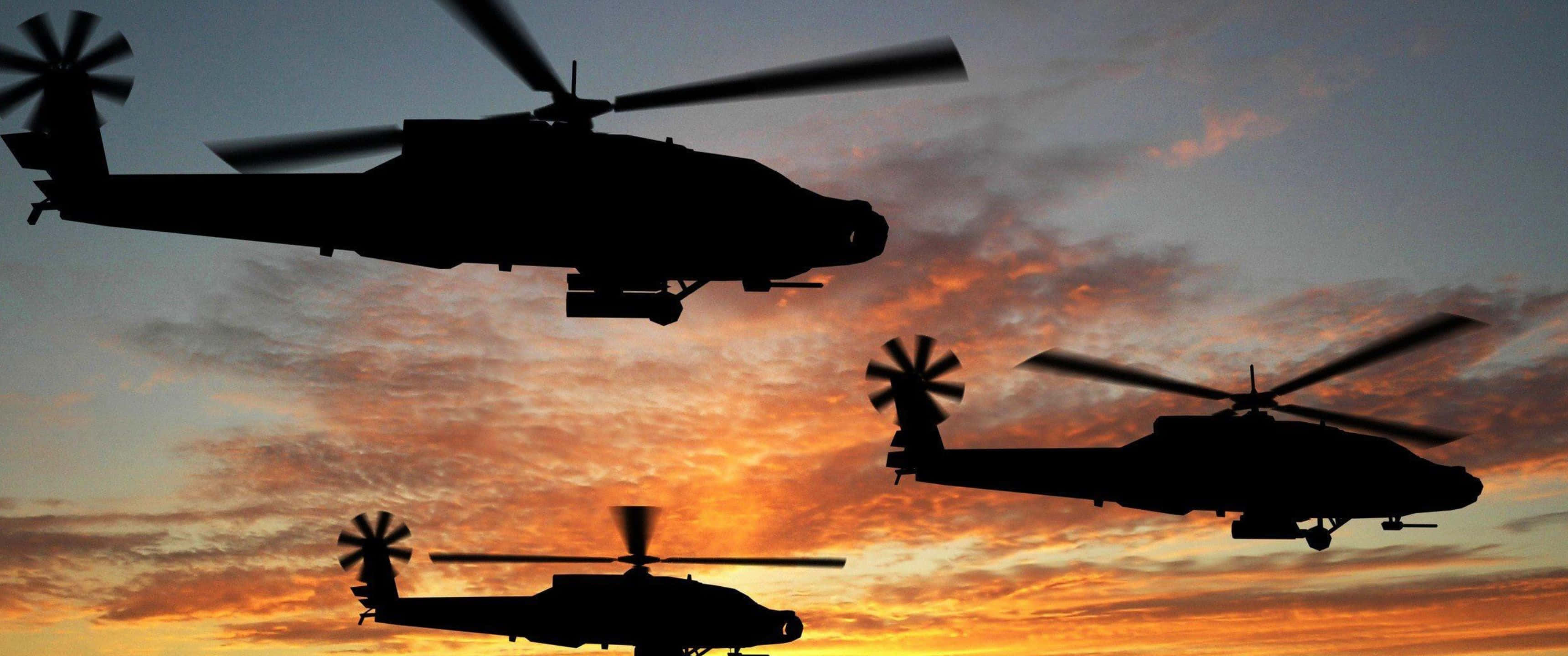 3440x1440p Helicopters 桌布 壁紙 — 三架直升機的剪影在火紅的日落天空中翱翔，天空中有橙色和紫色的條紋雲。