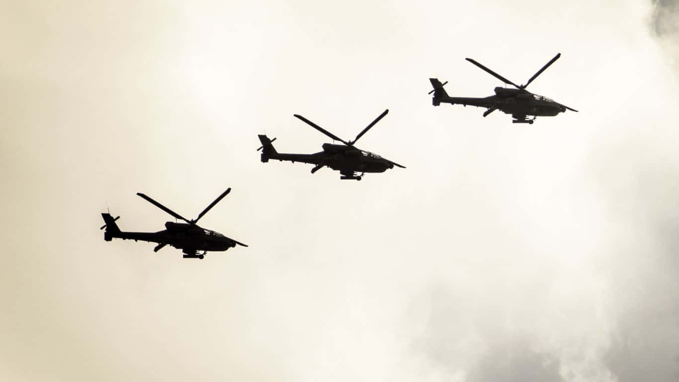 1366x768 Helicopters 桌布 壁紙 — 三架軍用直升機以黑色剪影形式編隊飛行，背景是明亮的陰天。