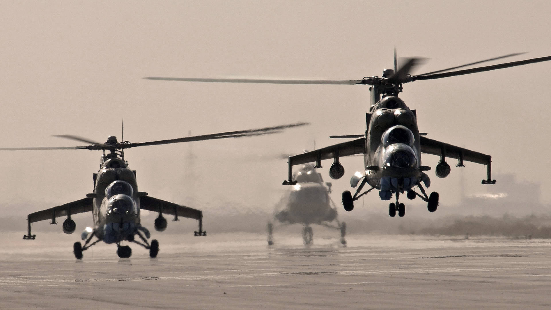 Helicopter 桌布 壁紙 — 三架軍用直升機低空盤旋在一個塵土飛揚的機場，在朦朧的沙漠環境中揚起沙塵。