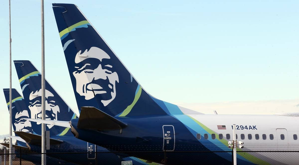 飛機 桌布 壁紙 — 三架阿拉斯加航空飛機並排停放，其獨特的藍色尾翼上帶有白色阿拉斯加原住民面孔標誌，背景是晴朗的天空。