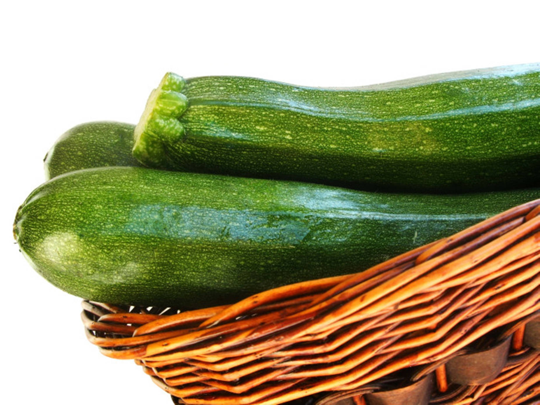 Healthy Food 桌布 壁紙 — 三條光澤的綠色櫛瓜放在編織柳條籃中，背景為純白色。