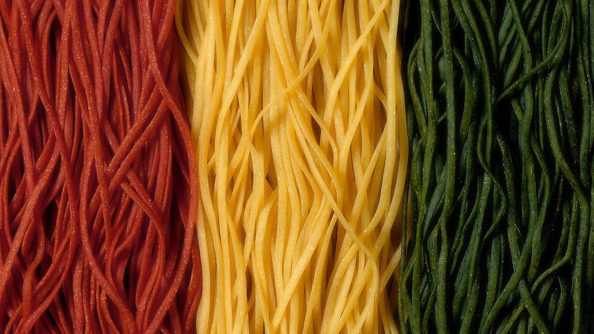 Pasta 桌布 壁紙 — 三條鮮豔的垂直條紋，由紅色、黃色和綠色的義大利麵條組成，特寫細節。