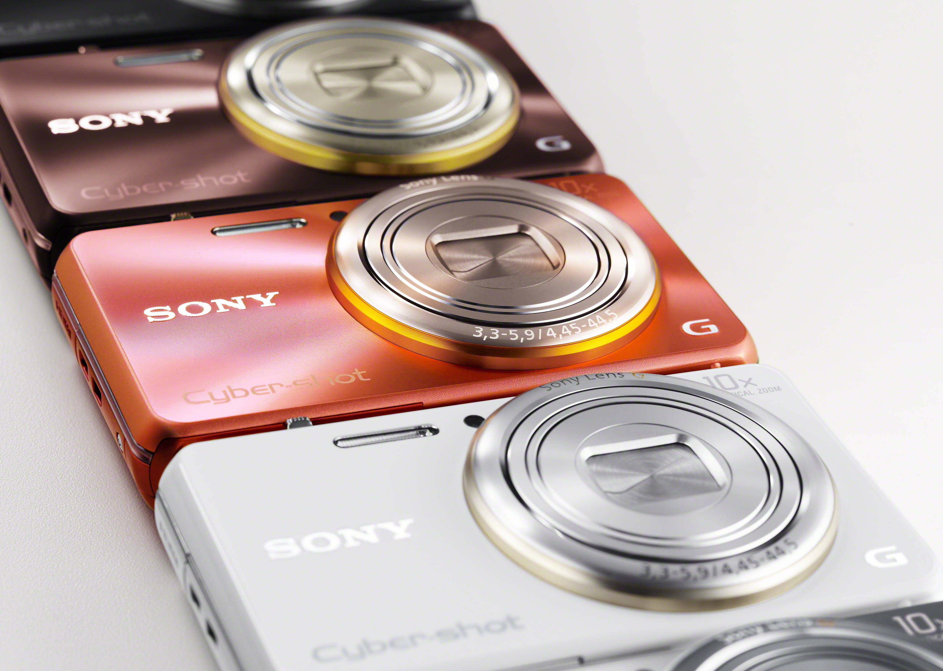 Sony 桌布 壁紙 — 三款Sony Cyber-shot輕便相機，分別為玫瑰金、橙色和白色，對角排列在潔白的表面上。