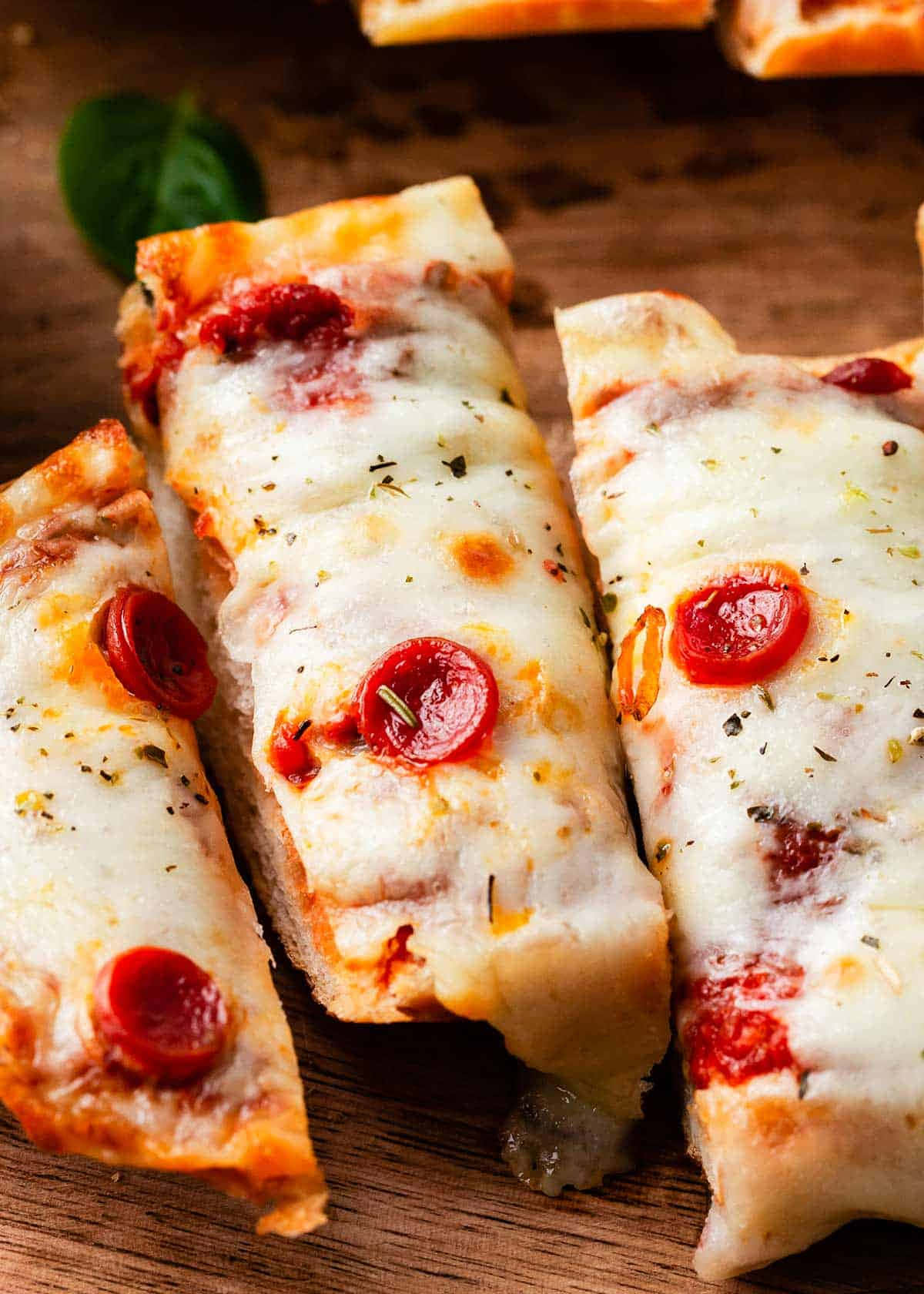 Pizza 桌布 壁紙 — 三片義大利辣香腸披薩，配上融化的起司和香草，放在質樸的木板上。