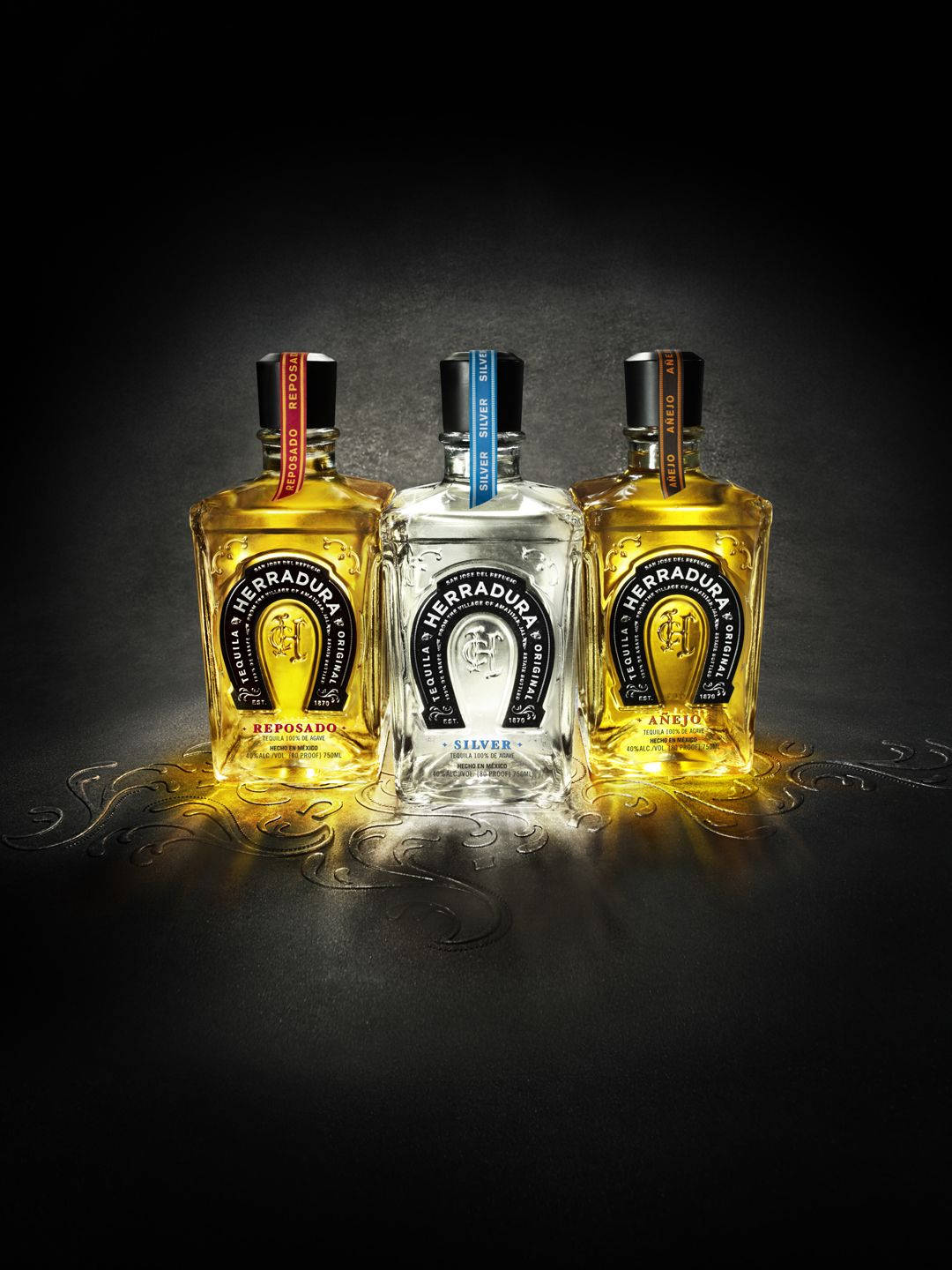 手機 桌布 壁紙 — 三瓶 Herradura 龍舌蘭酒在黑暗背景上被照亮，帶有華麗的金色液體反射。