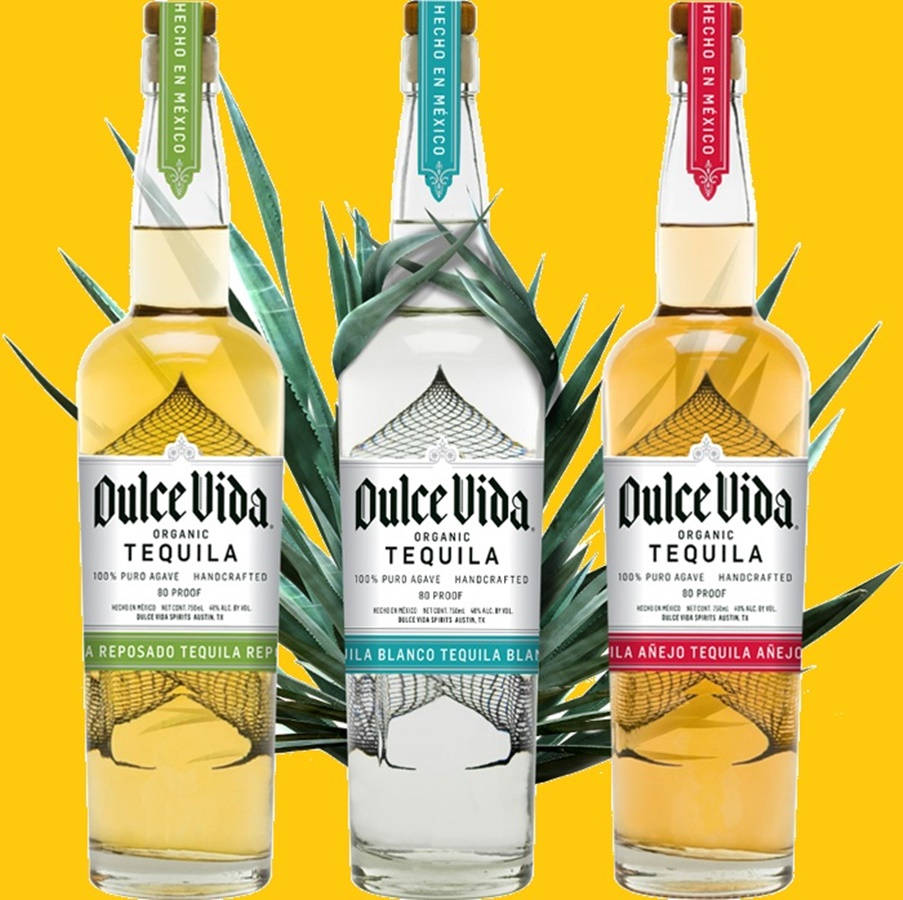 cocktail 桌布 壁紙 — 三瓶Dulce Vida龍舌蘭酒（reposado、blanco和añejo品種）在鮮黃色背景前與龍舌蘭葉一同展示。