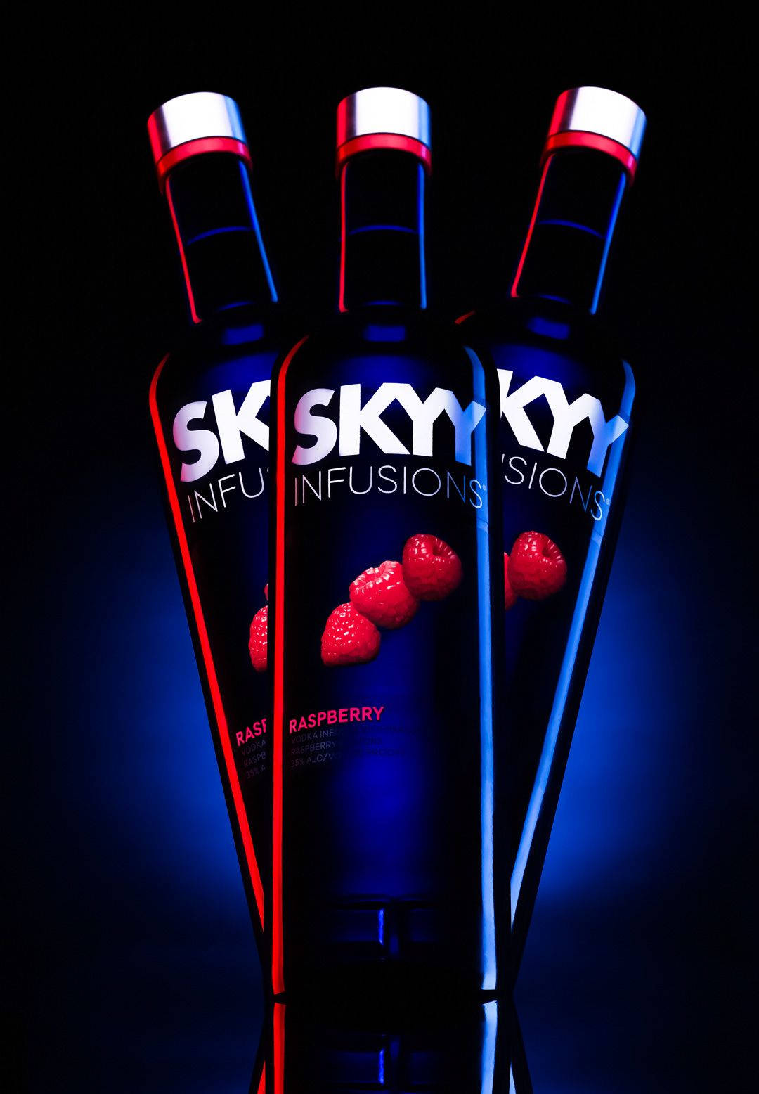 alcohol 桌布 壁紙 — 三瓶SKYY Raspberry Infusions伏特加酒在黑色背景上發出紅色和藍色霓虹燈光。