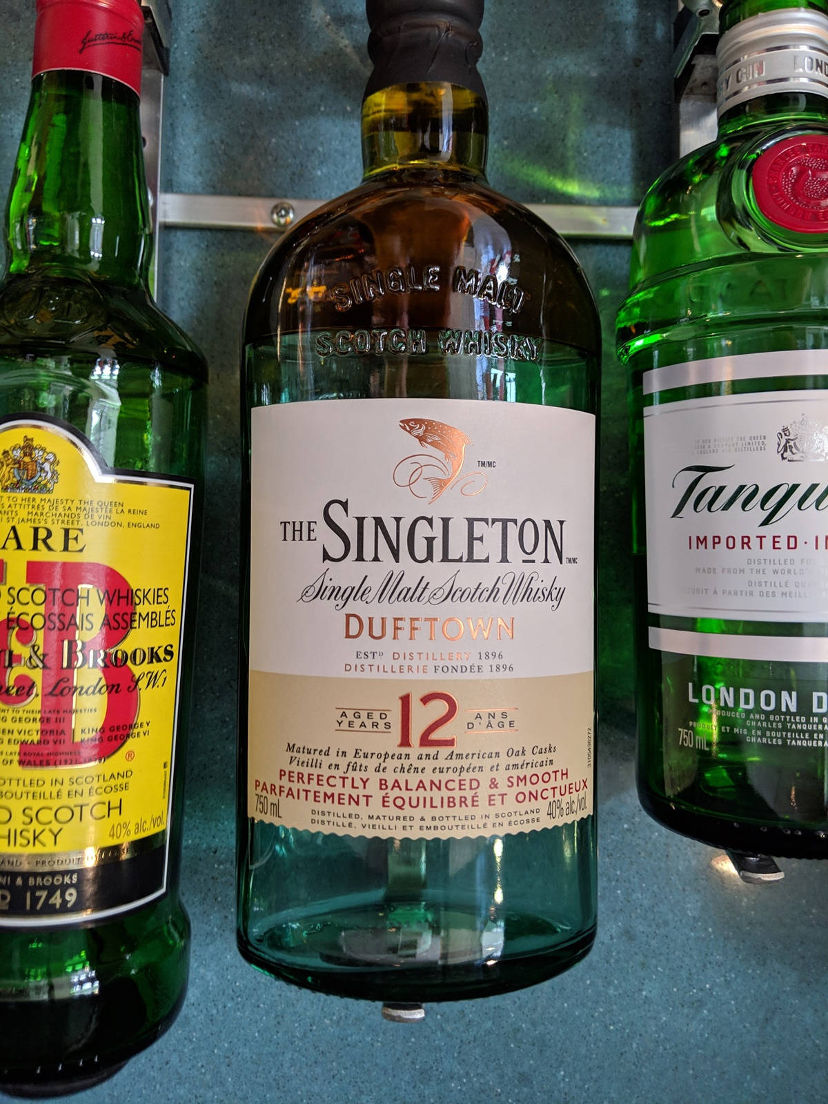 bottle 桌布 壁紙 — 三瓶威士忌，包括The Singleton Dufftown 12年，放在一個綠色架子上，標籤清晰可見。
